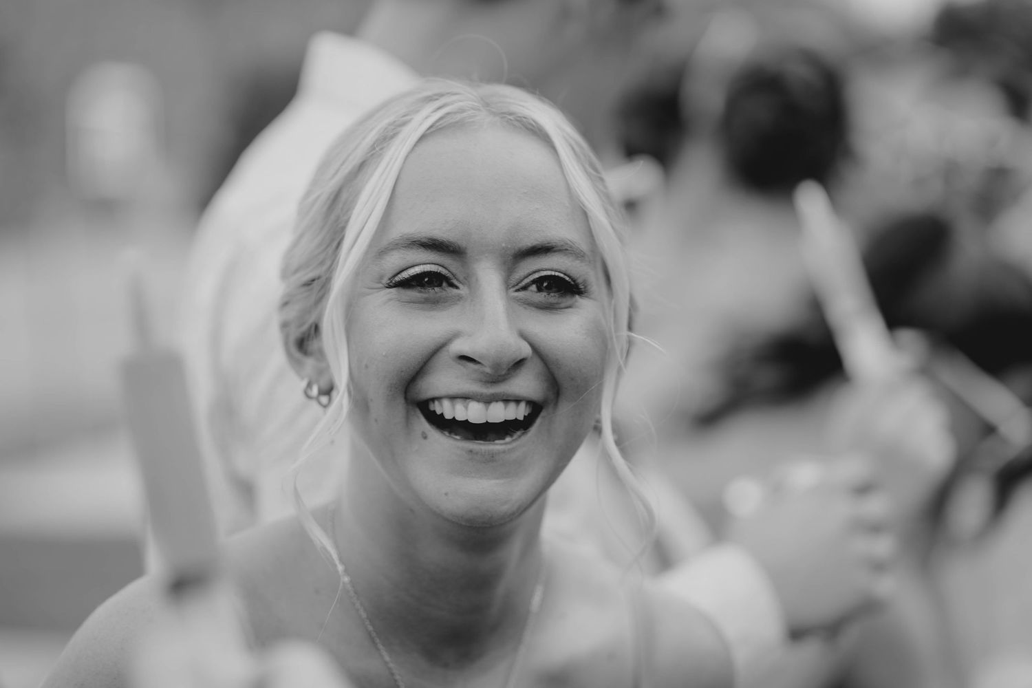 Black and white close-up of radiant bride laughing joyfully during wedding celebration.