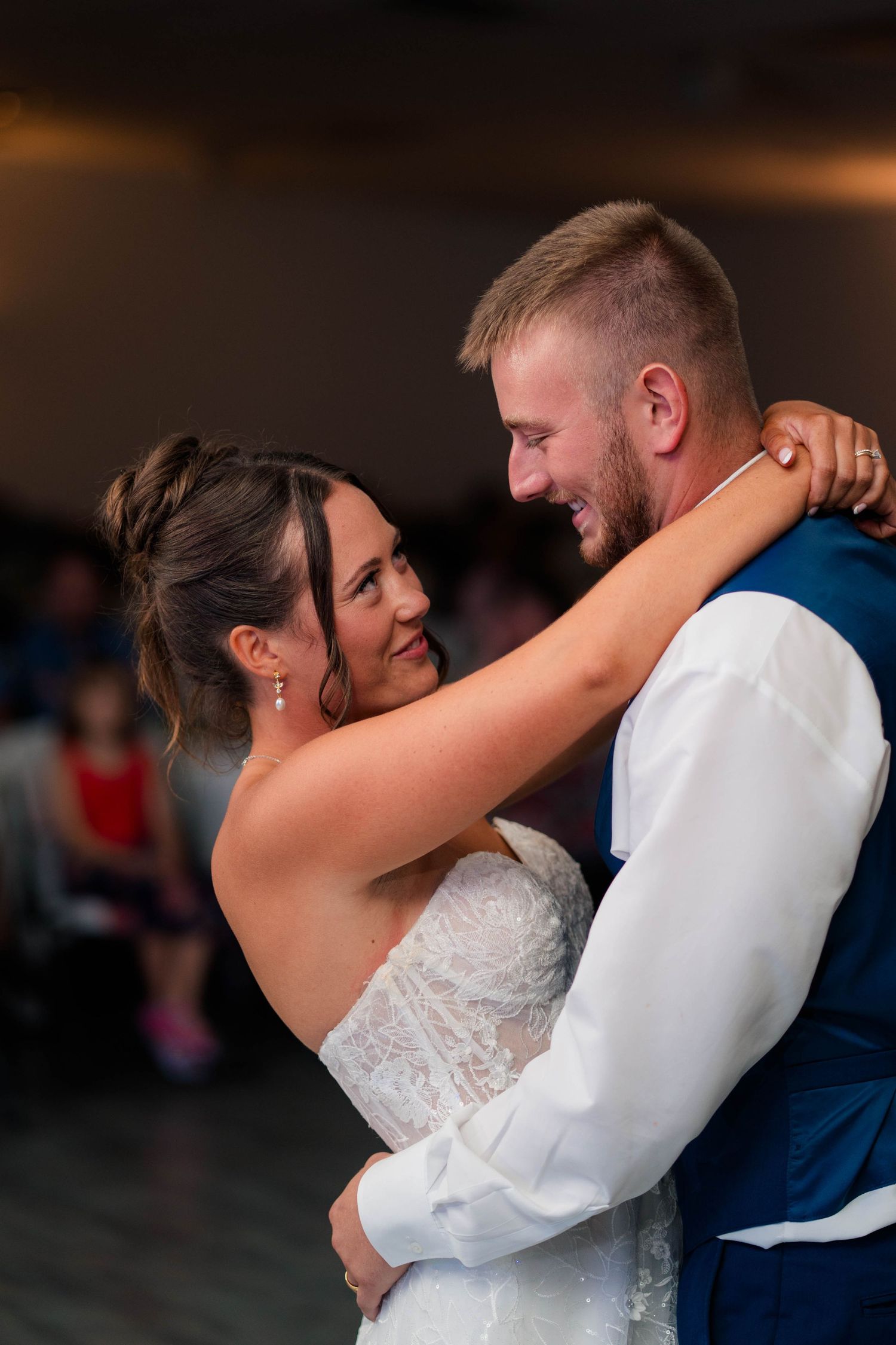 Bride and groom share an intimate first dance, smiling at each other during their wedding reception.