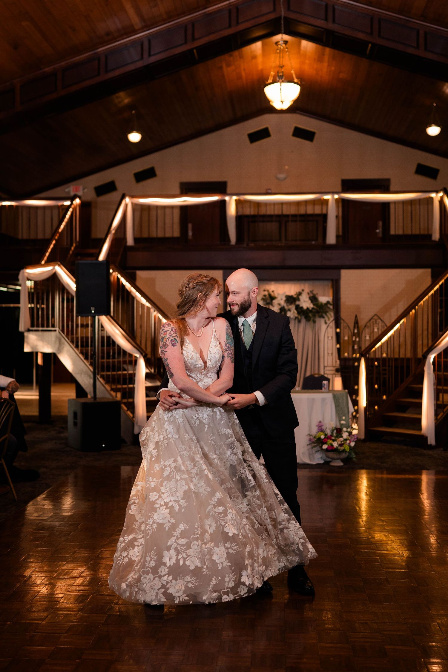 Bride and groom share their first dance in an elegant wedding venue with warm lighting and grand staircases.