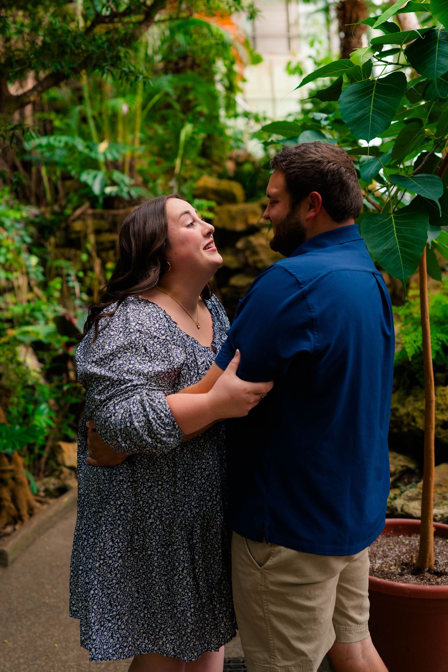 Couple laughing and embracing in a lush tropical greenhouse botanical garden.