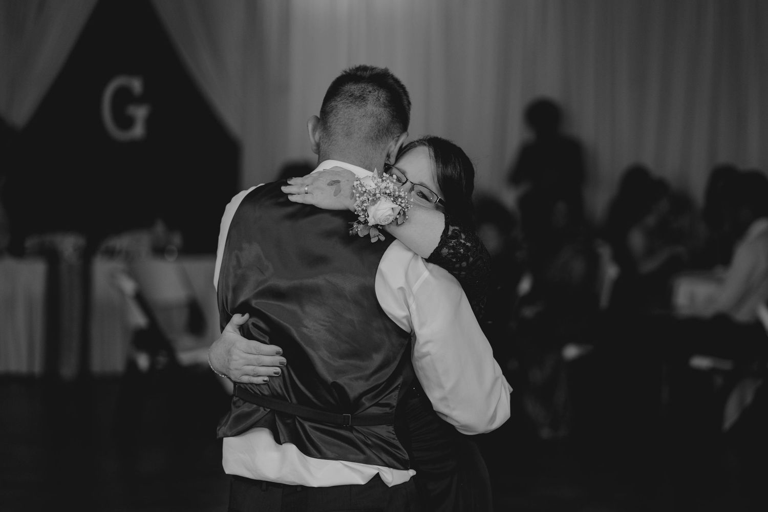 Black and white photo of groom and woman sharing a tender embrace during mother-son wedding dance.
