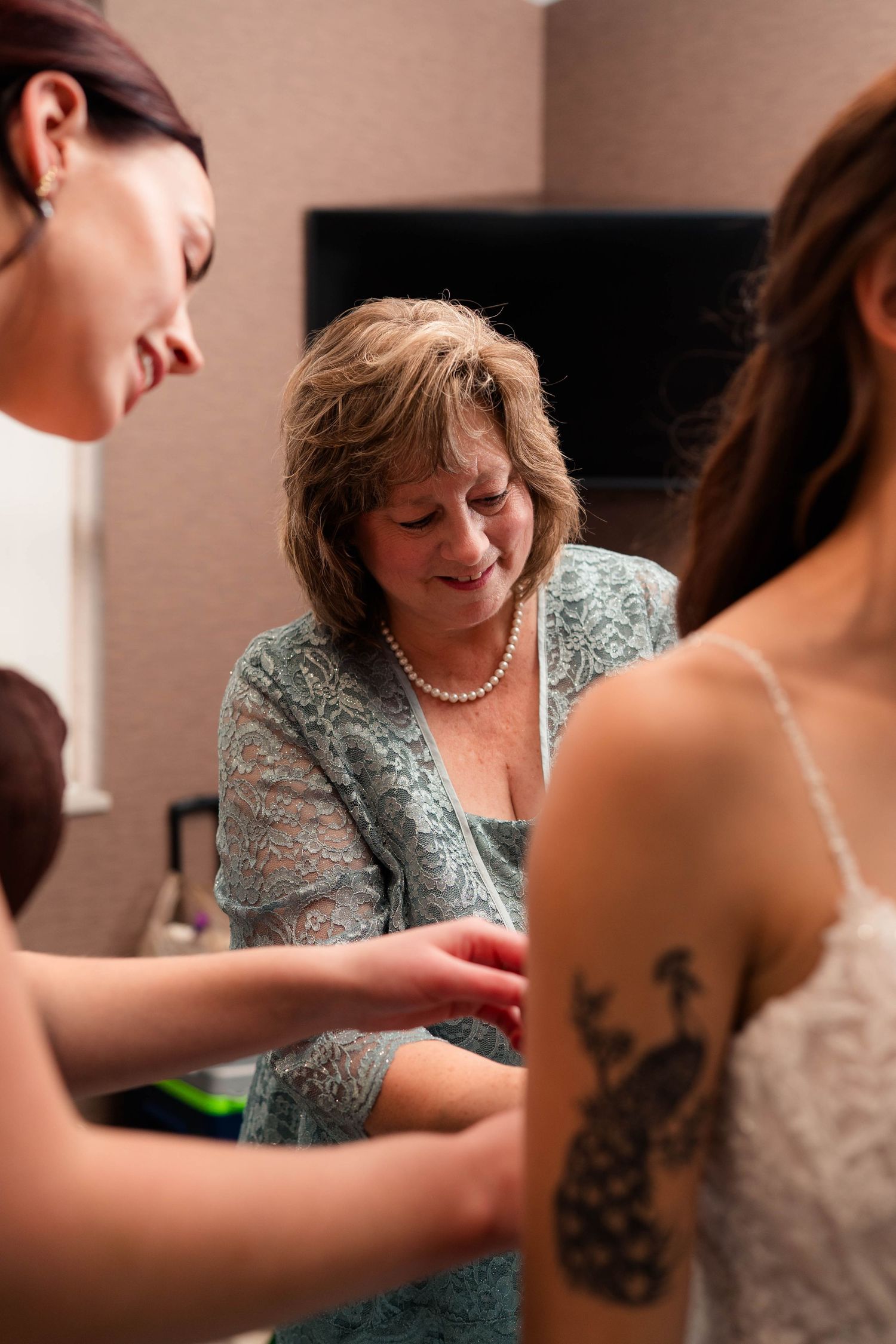 Mother of the bride helping bride with bracelet while getting ready for wedding day.