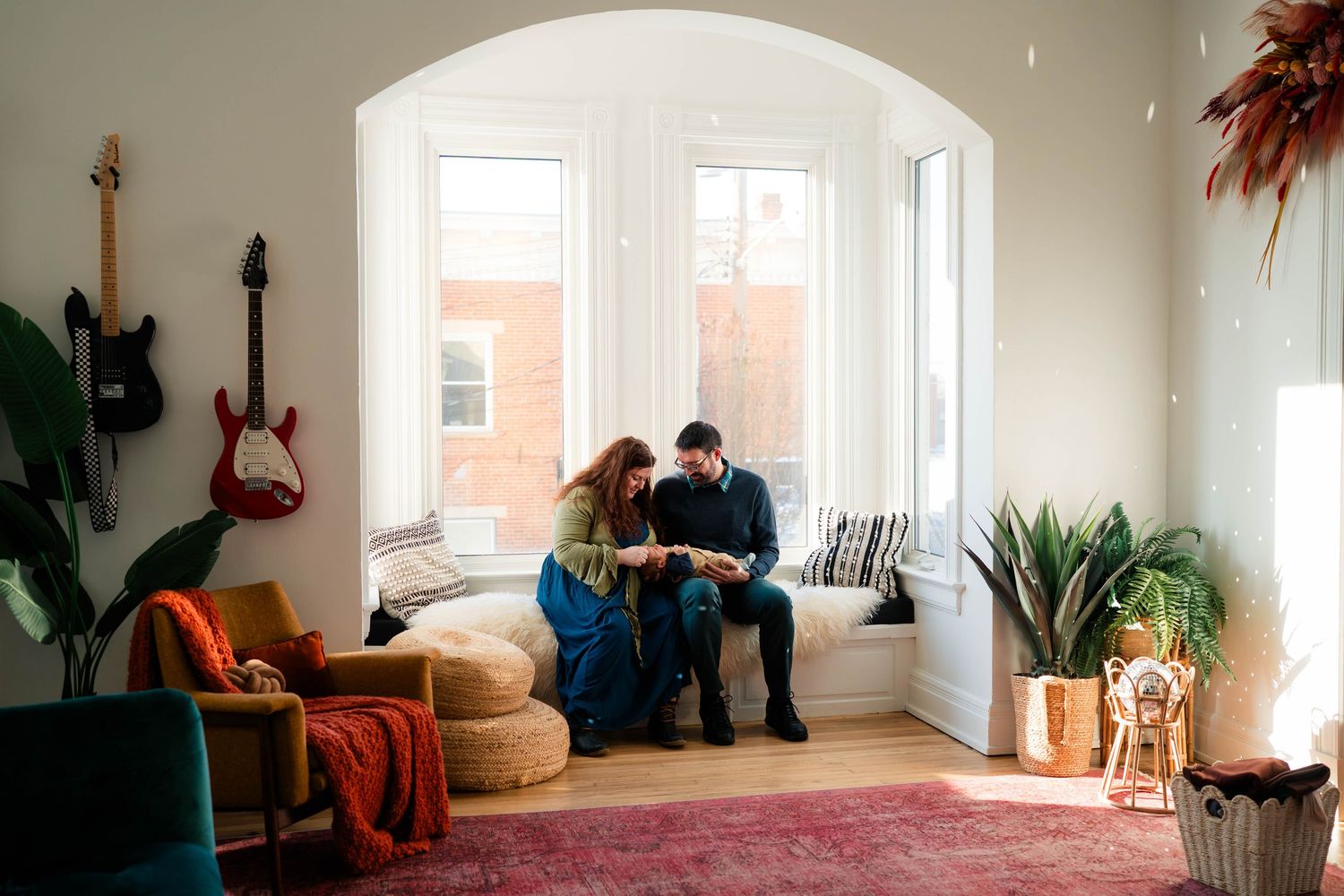 Young couple sitting together in colorful bohemian living room with guitars on wall.