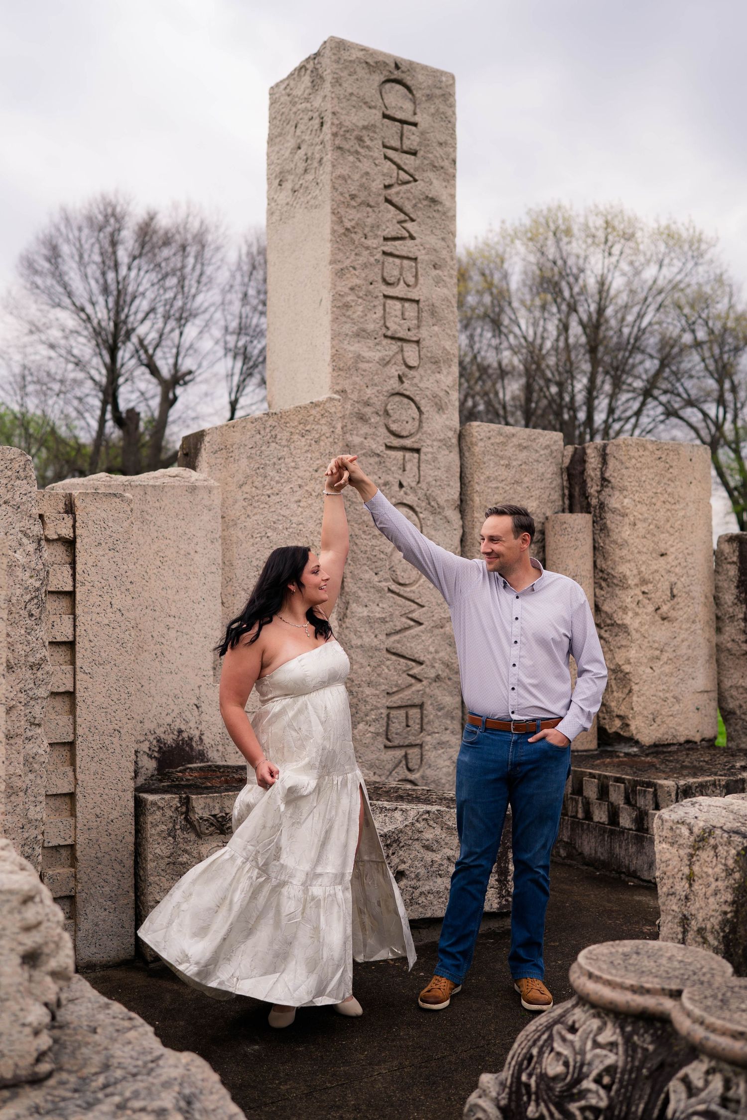 Couple dancing among stone ruins at Chamber of Commerce monument during engagement photo session.