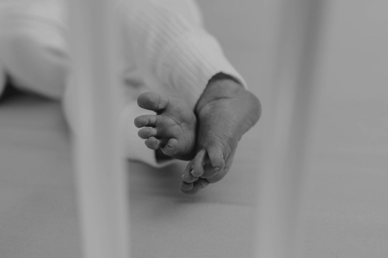 Close-up black and white photo of precious newborn baby feet resting gently together.