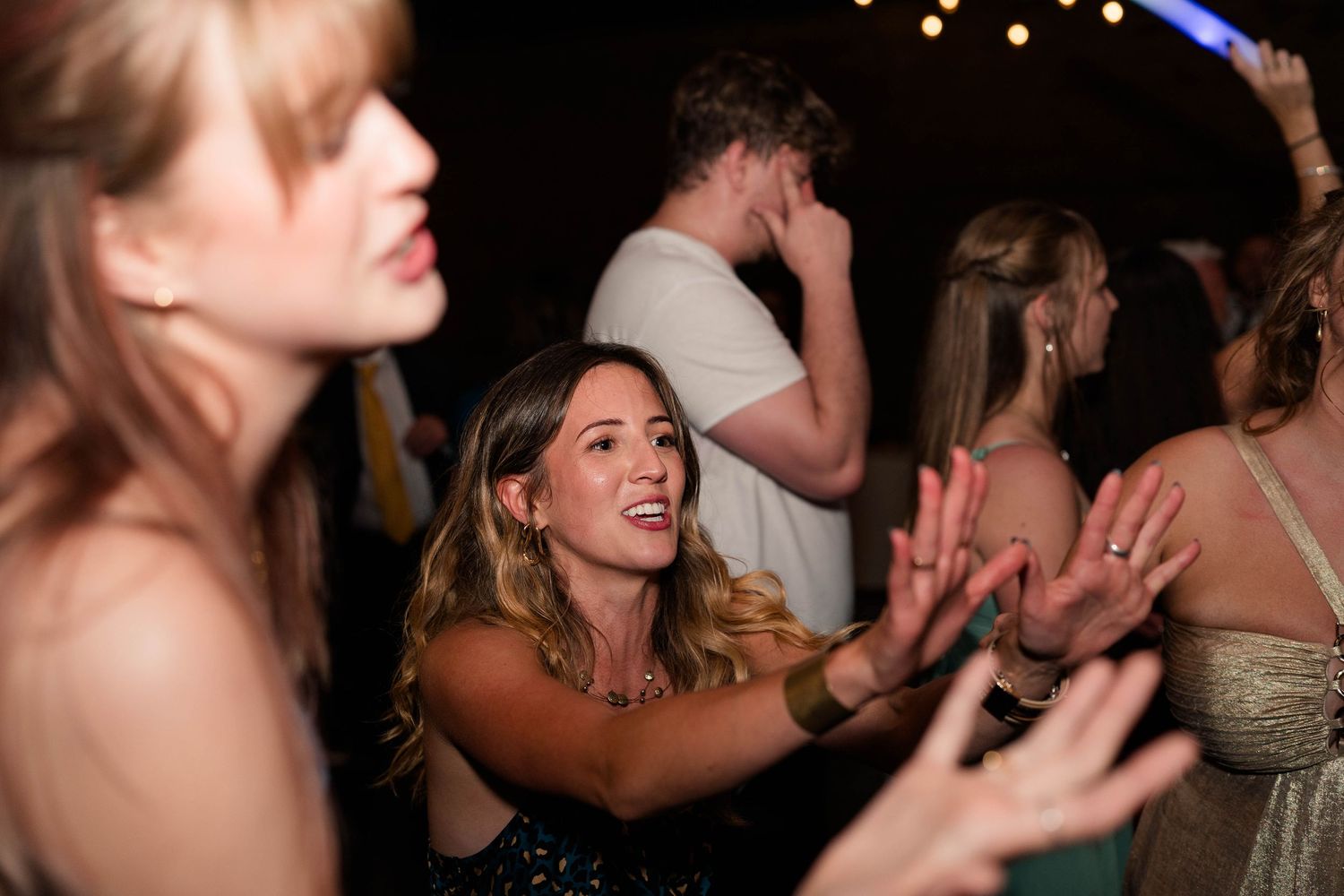 Excited wedding guest clapping and dancing enthusiastically at lively outdoor wedding reception.
