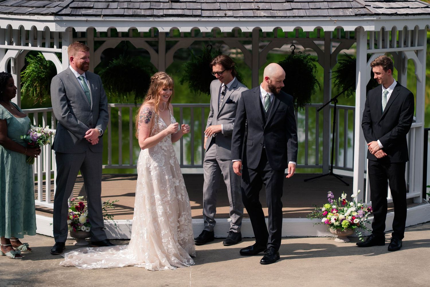 Wedding party stands at a gazebo altar as bride and groom exchange vows outdoors.