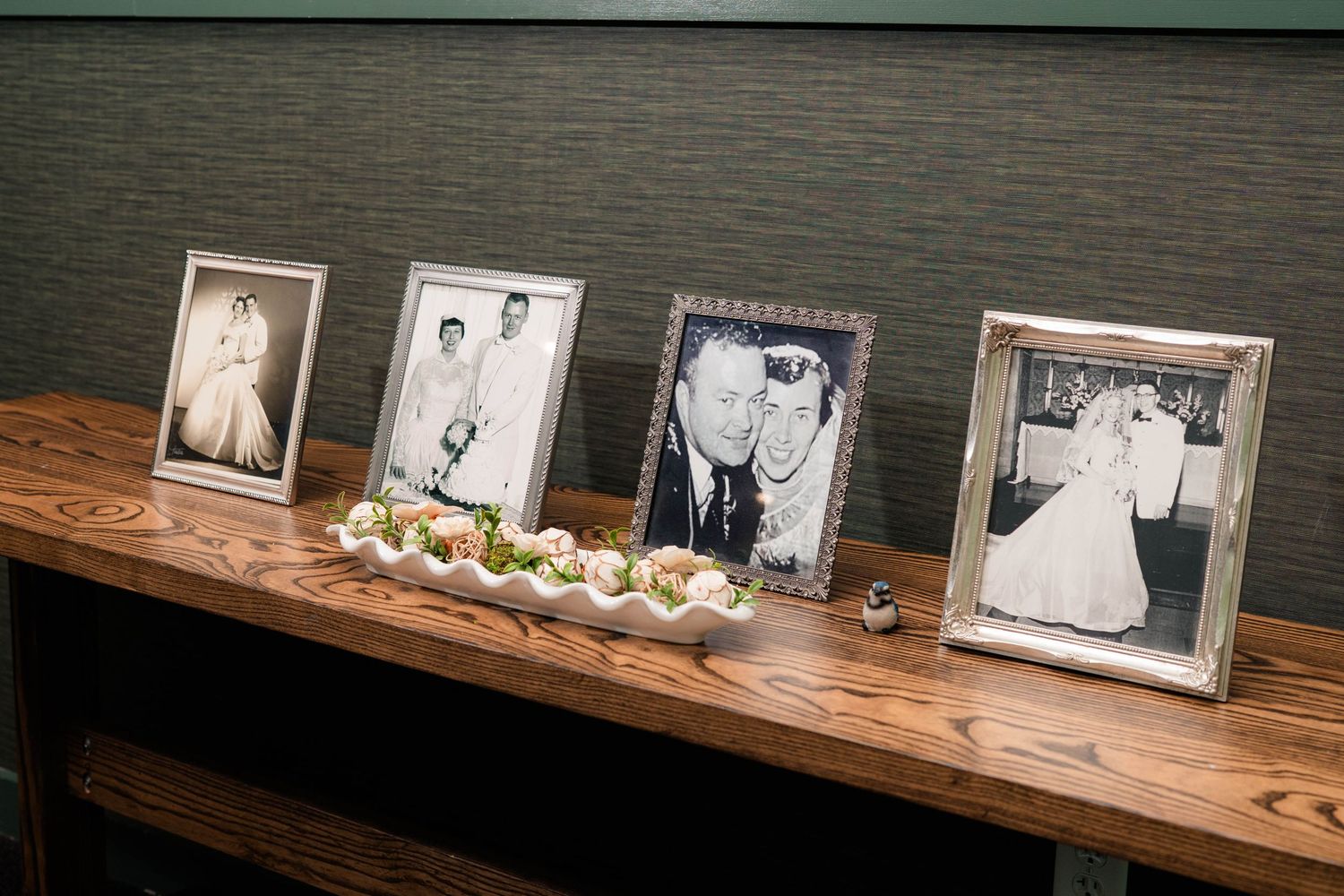 Four framed black and white vintage wedding photos displayed on a wooden table at a wedding reception.