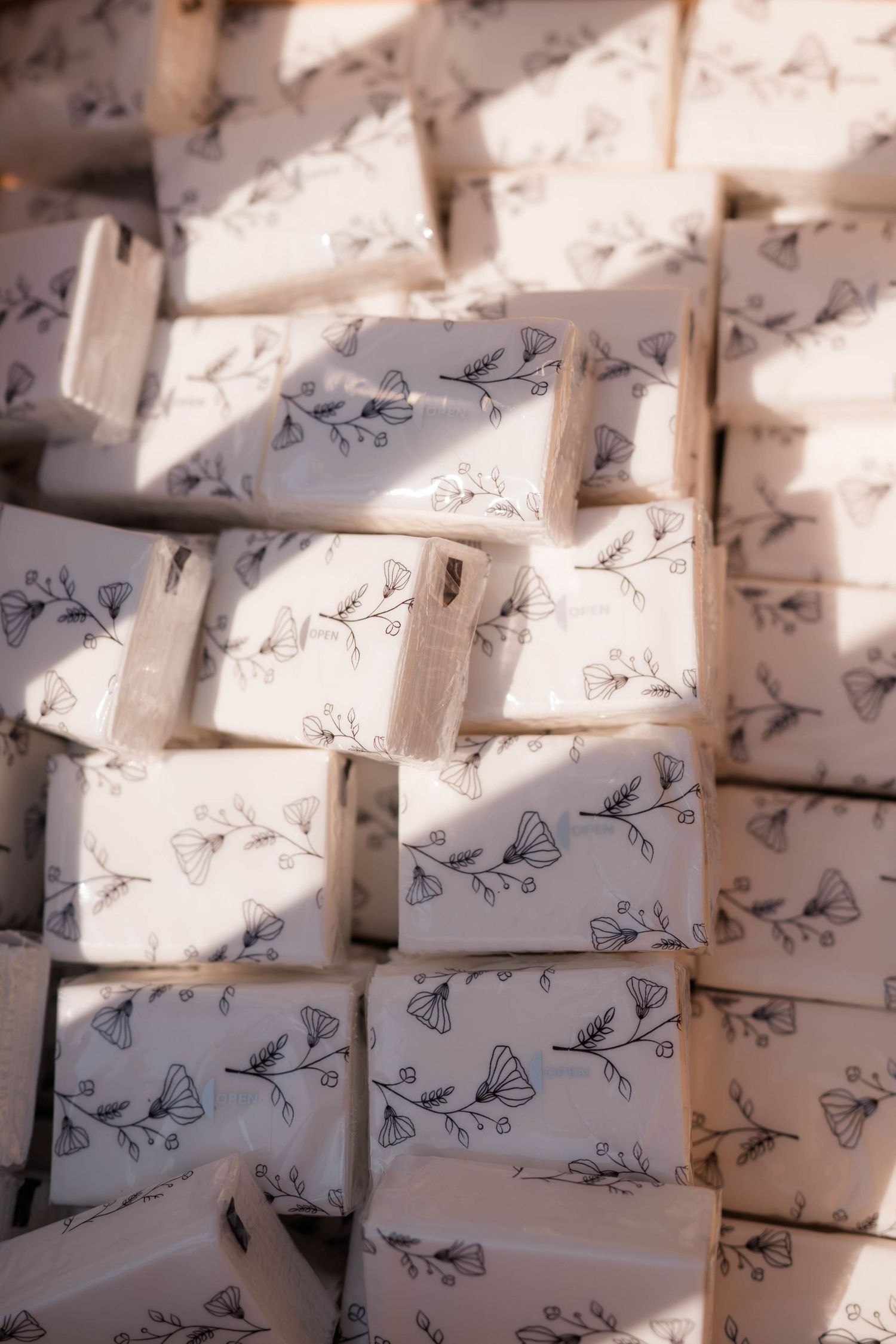 Handmade artisan soaps wrapped in white paper with delicate floral butterfly prints stacked together.
