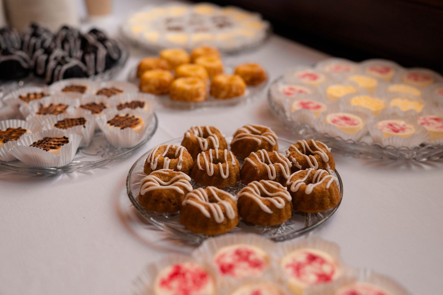 Assorted decorated mini desserts and pastries displayed on platters at a wedding reception.