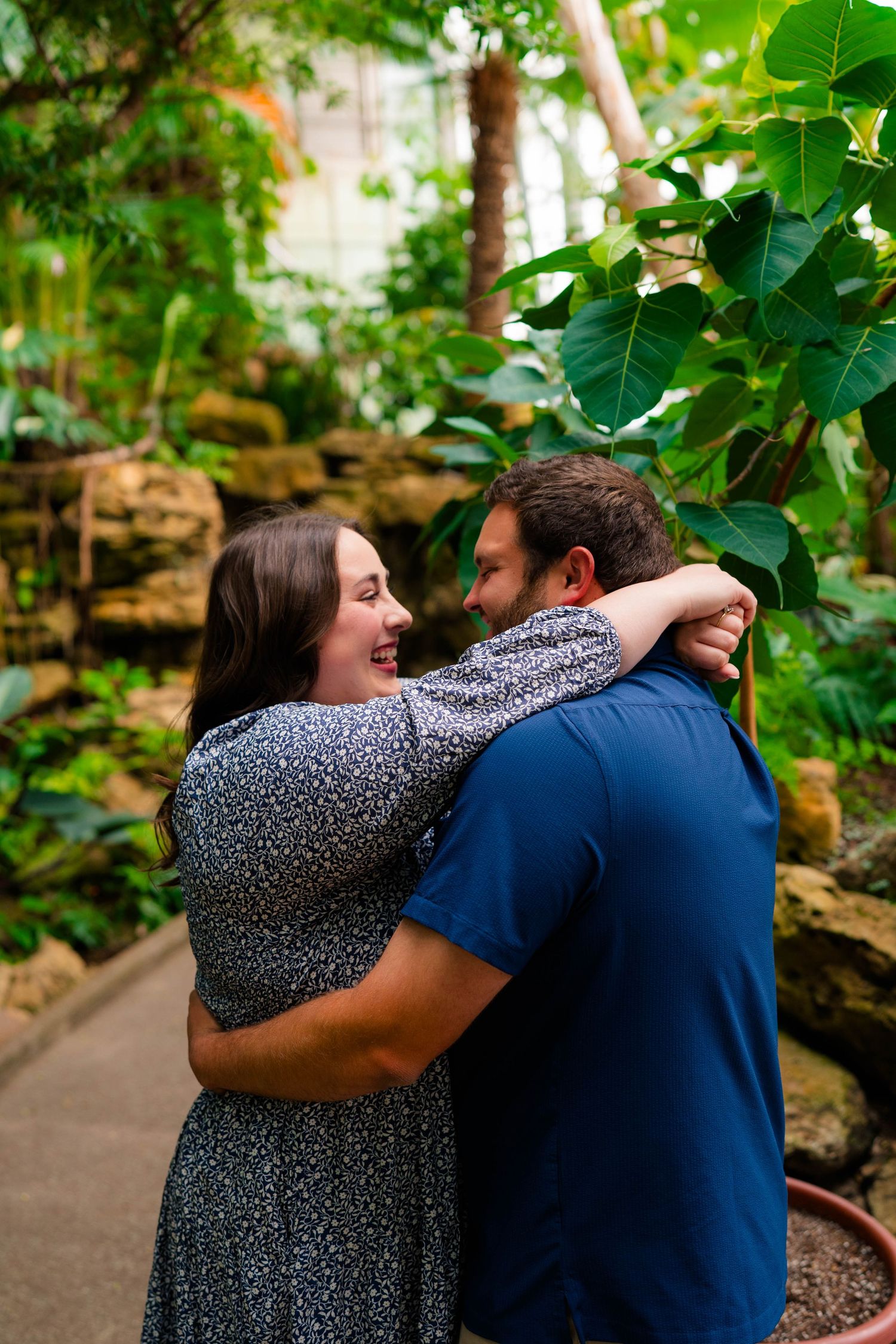 Happy couple hugging and laughing together in a tropical botanical garden.