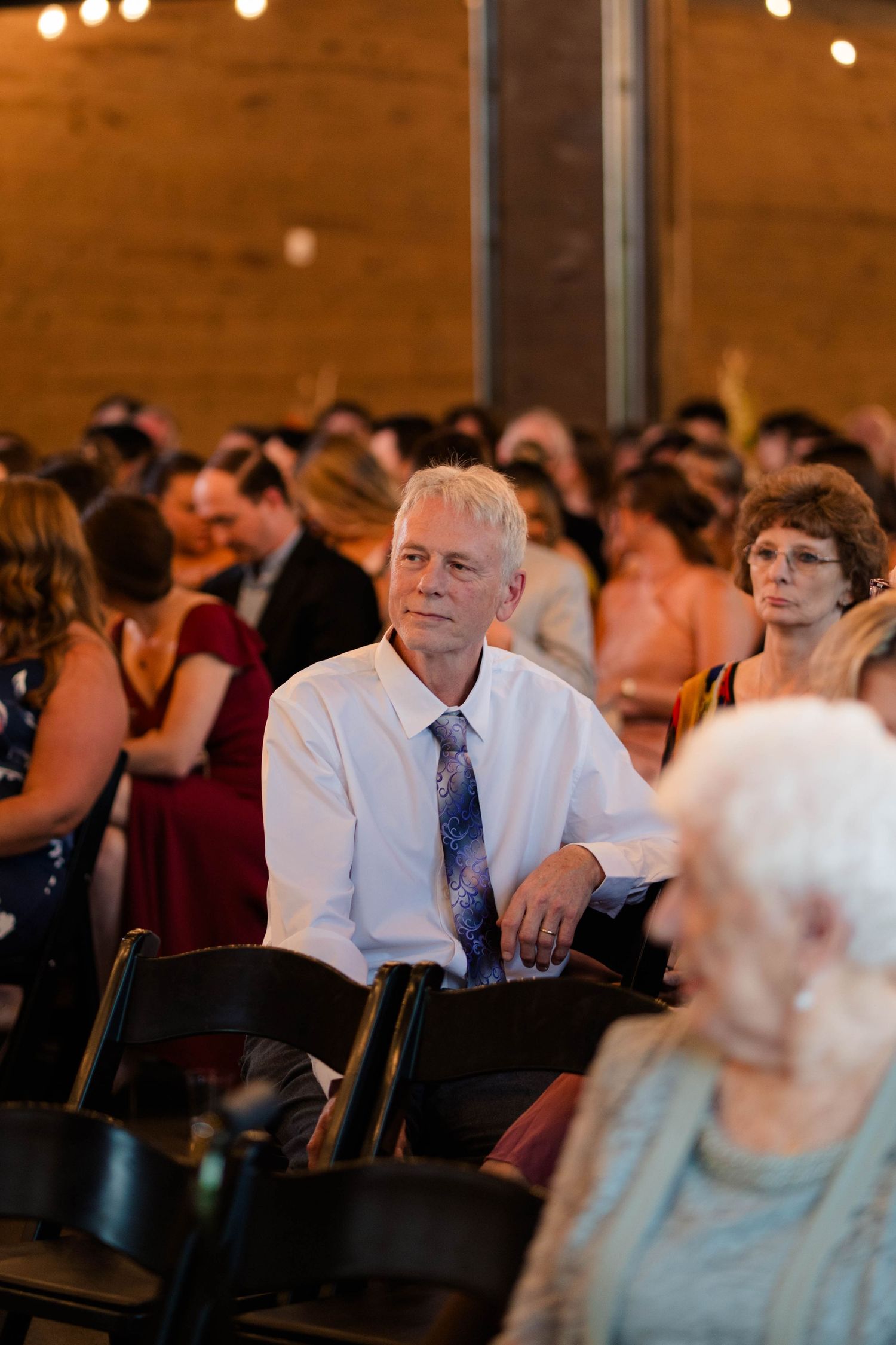 Wedding guests seated in rustic brick venue with warm lighting during ceremony.