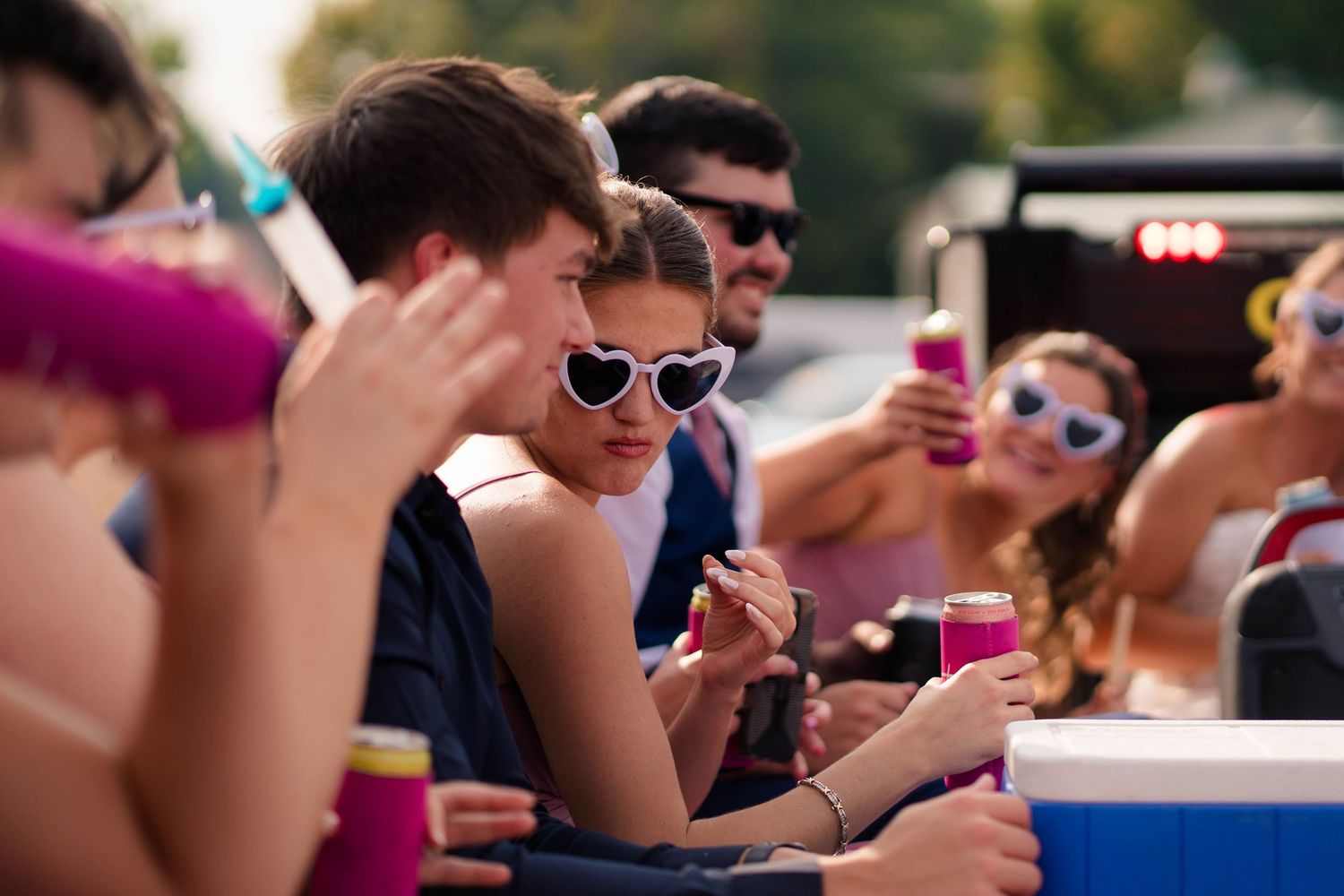 Young wedding guests wearing heart-shaped sunglasses enjoying outdoor wedding reception party.