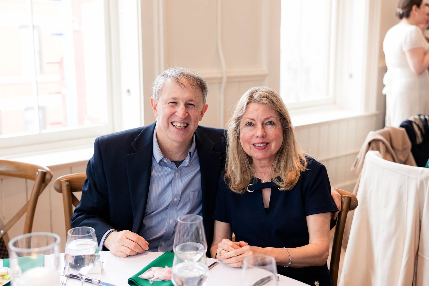 Smiling couple seated together at elegantly set dining table at formal event.