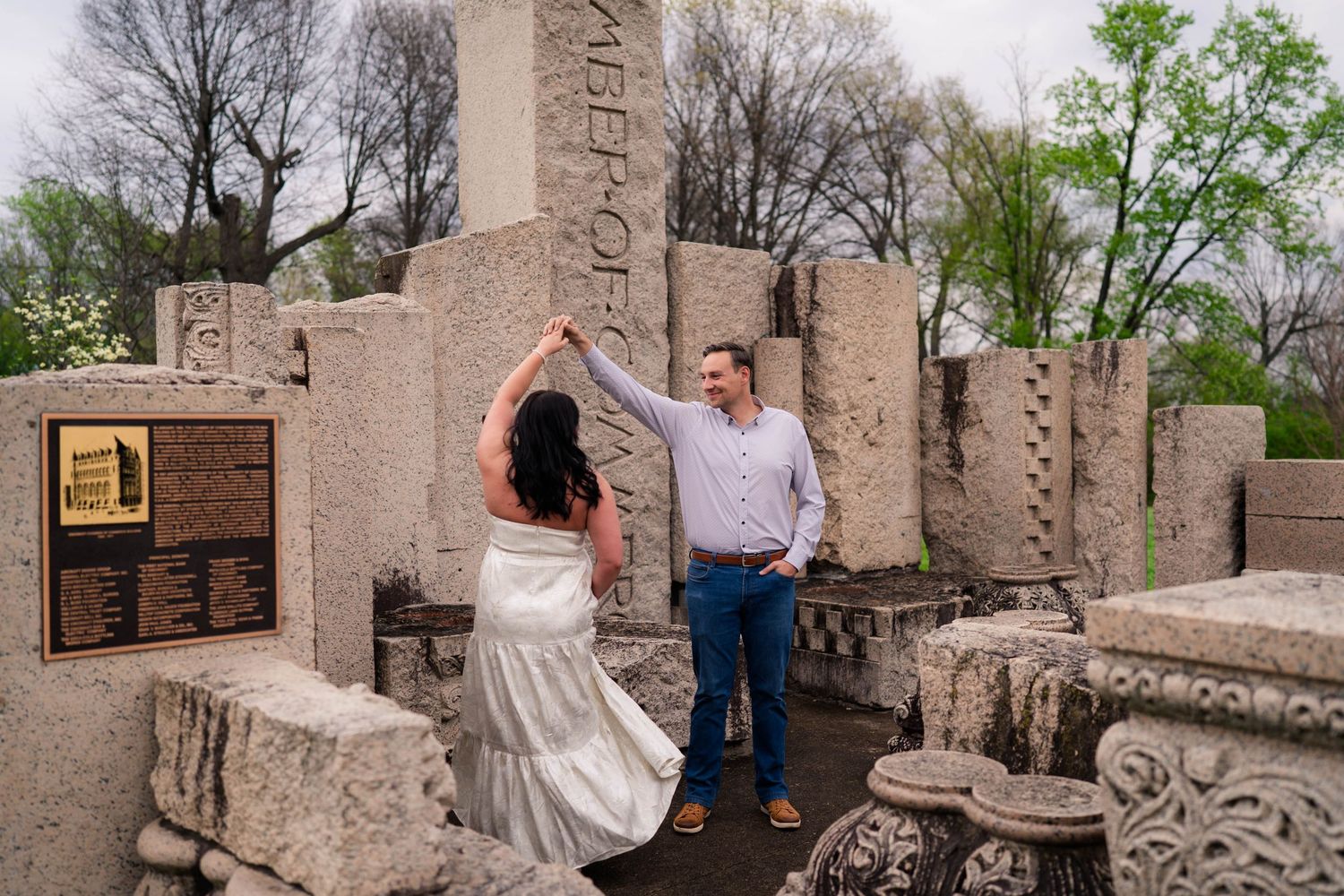 Couple dancing among ancient stone ruins and columns outdoors during an engagement photo session.