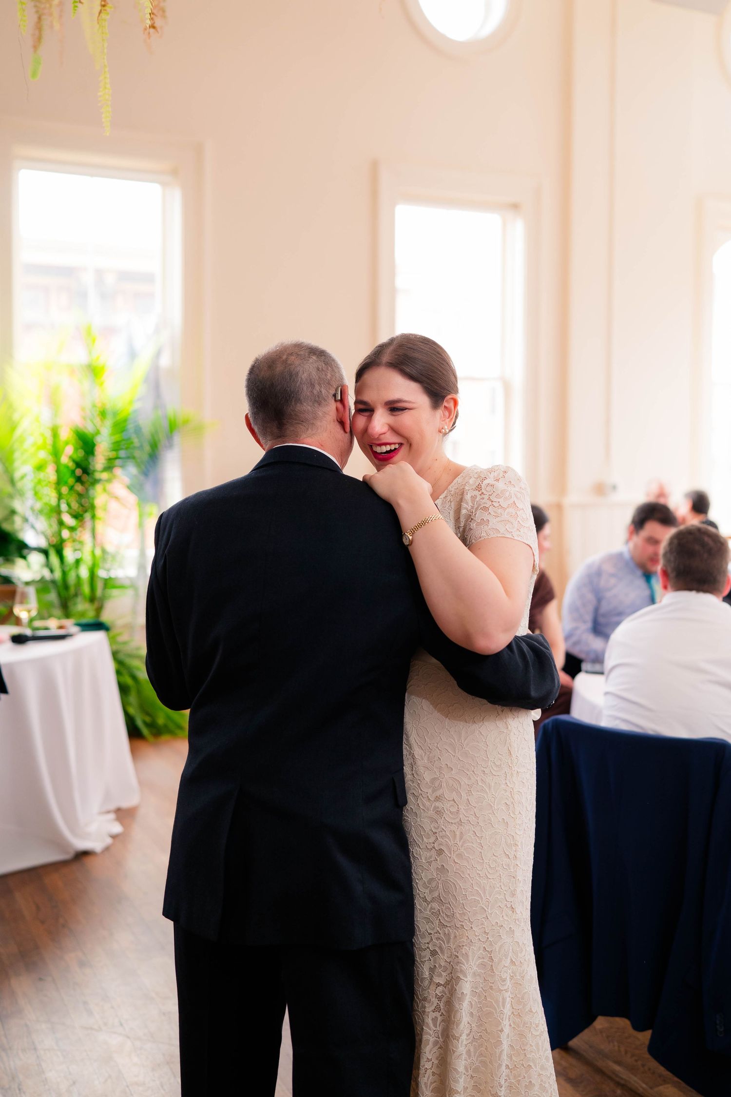 Bride laughing joyfully while sharing a father-daughter dance at elegant wedding reception.