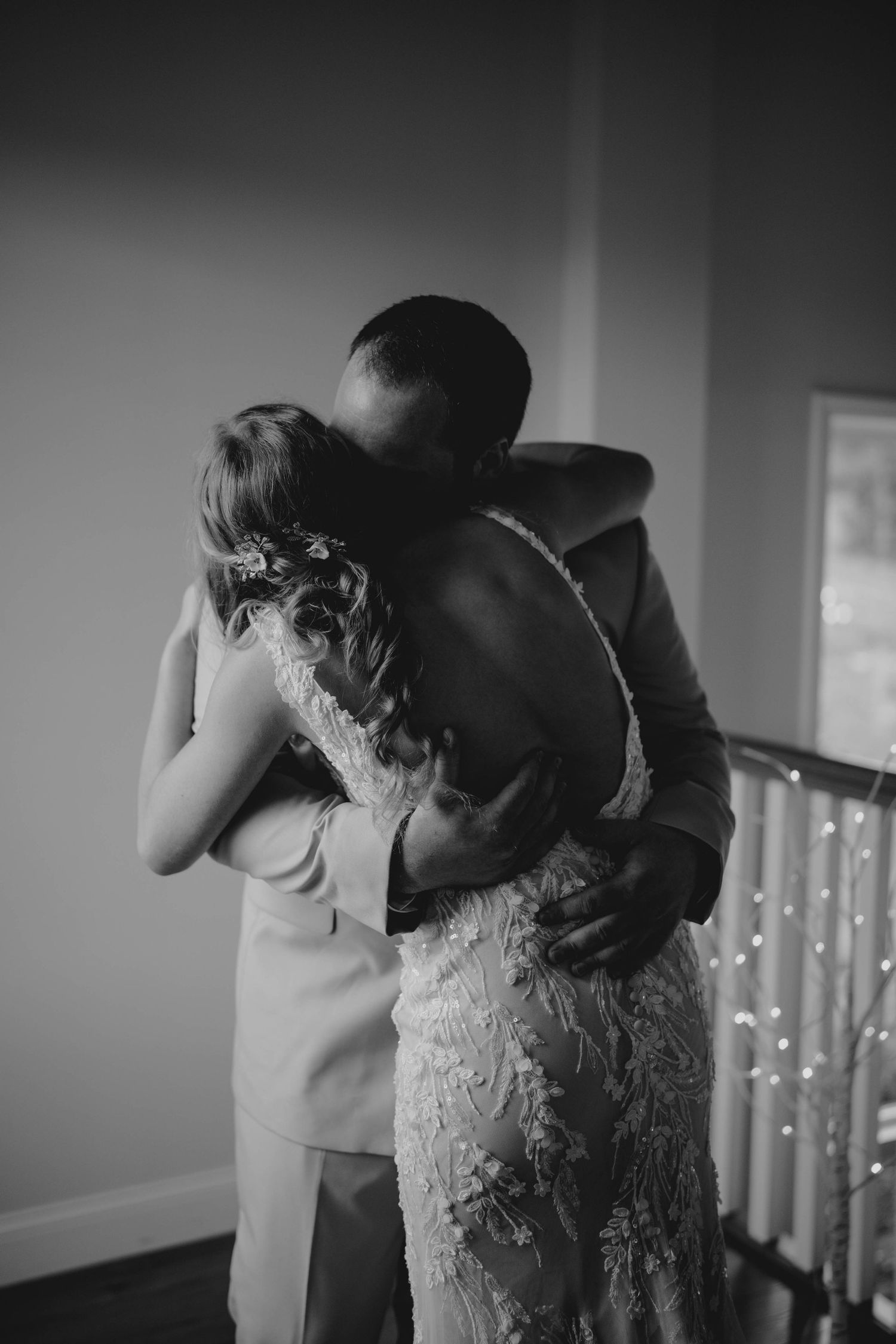 Black and white photo of bride and groom sharing an intimate embrace near a staircase.