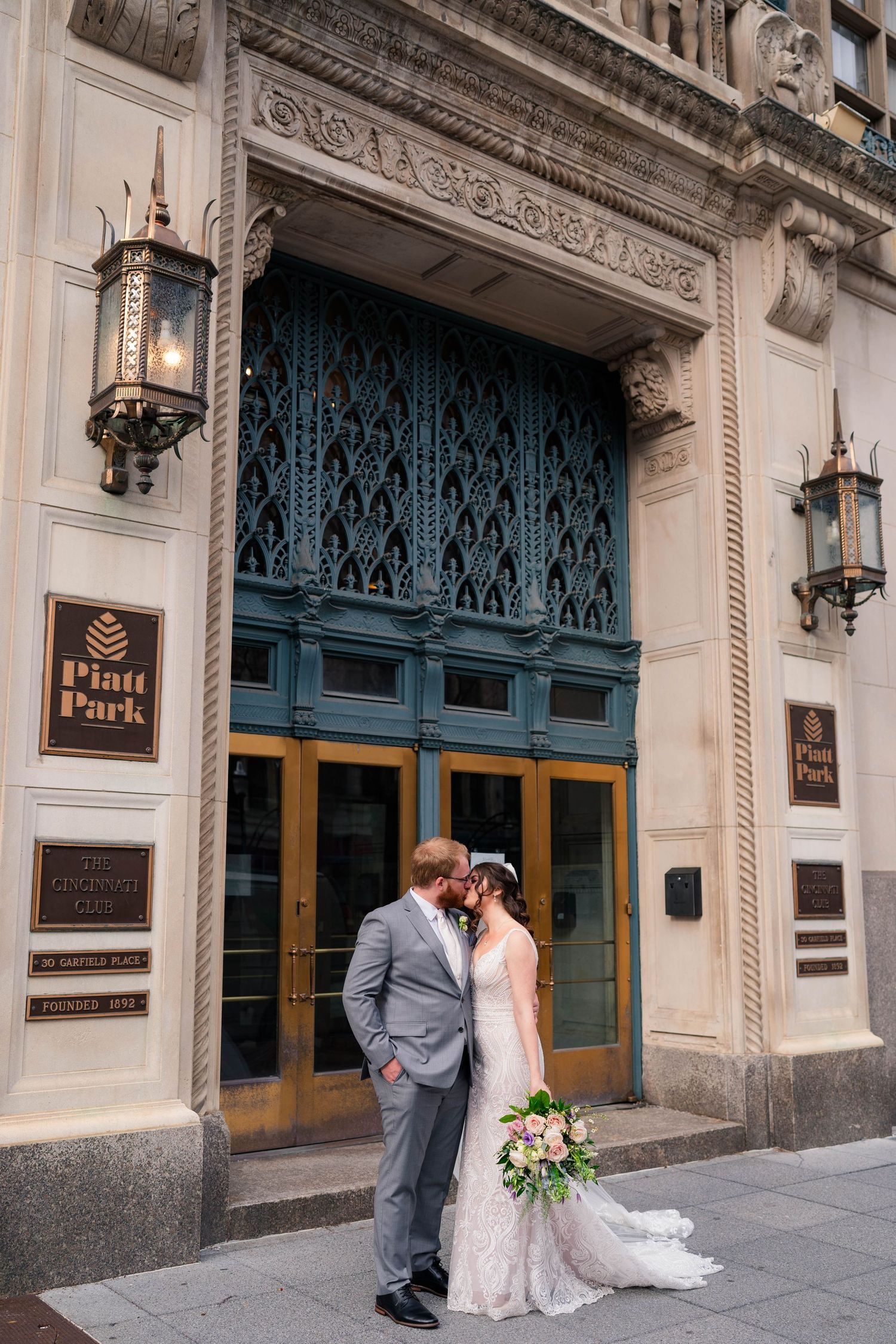 Bride and groom share a kiss outside the elegant Pratt Park building with ornate blue doors.
