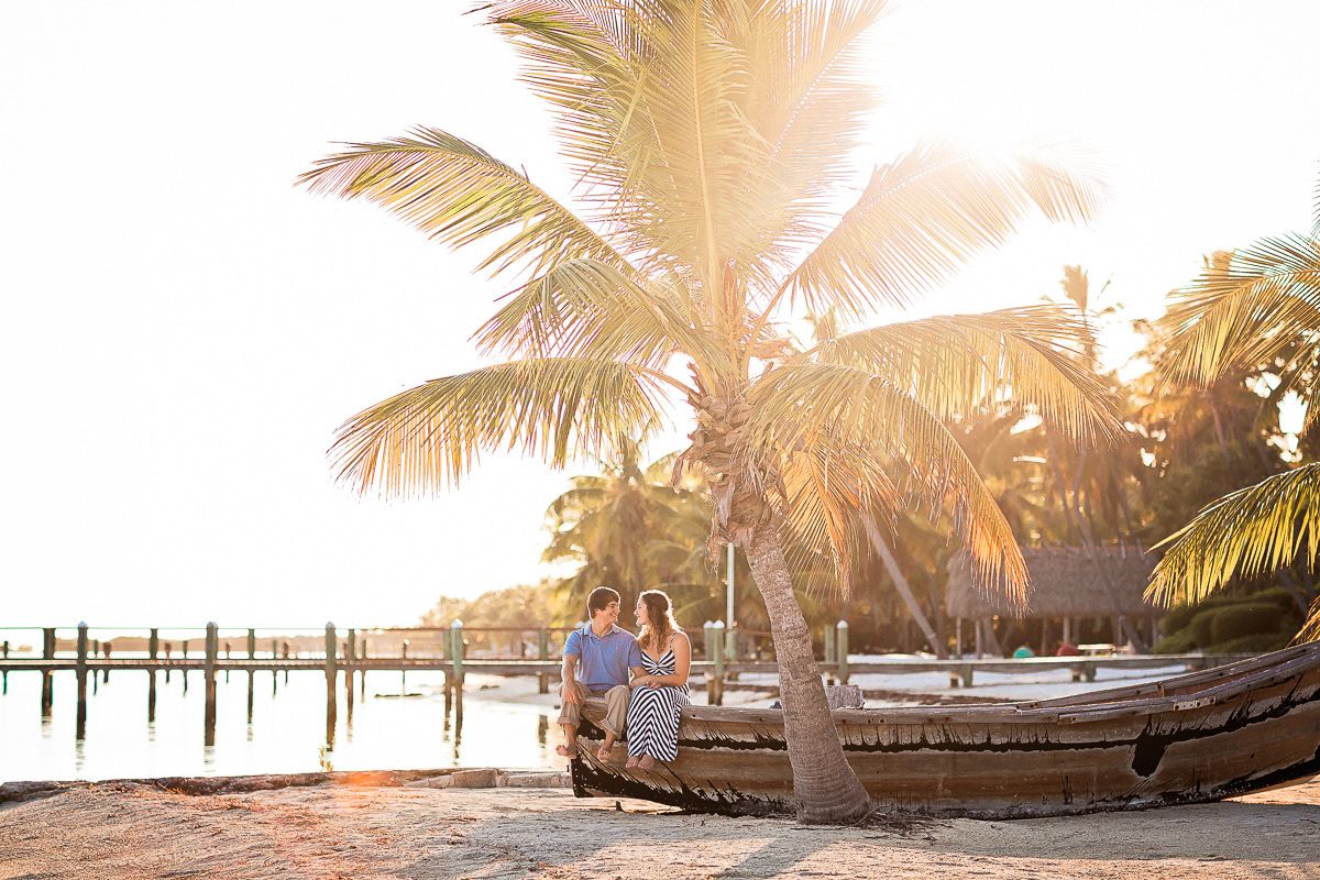 Couple sitting beneath palm trees by the water