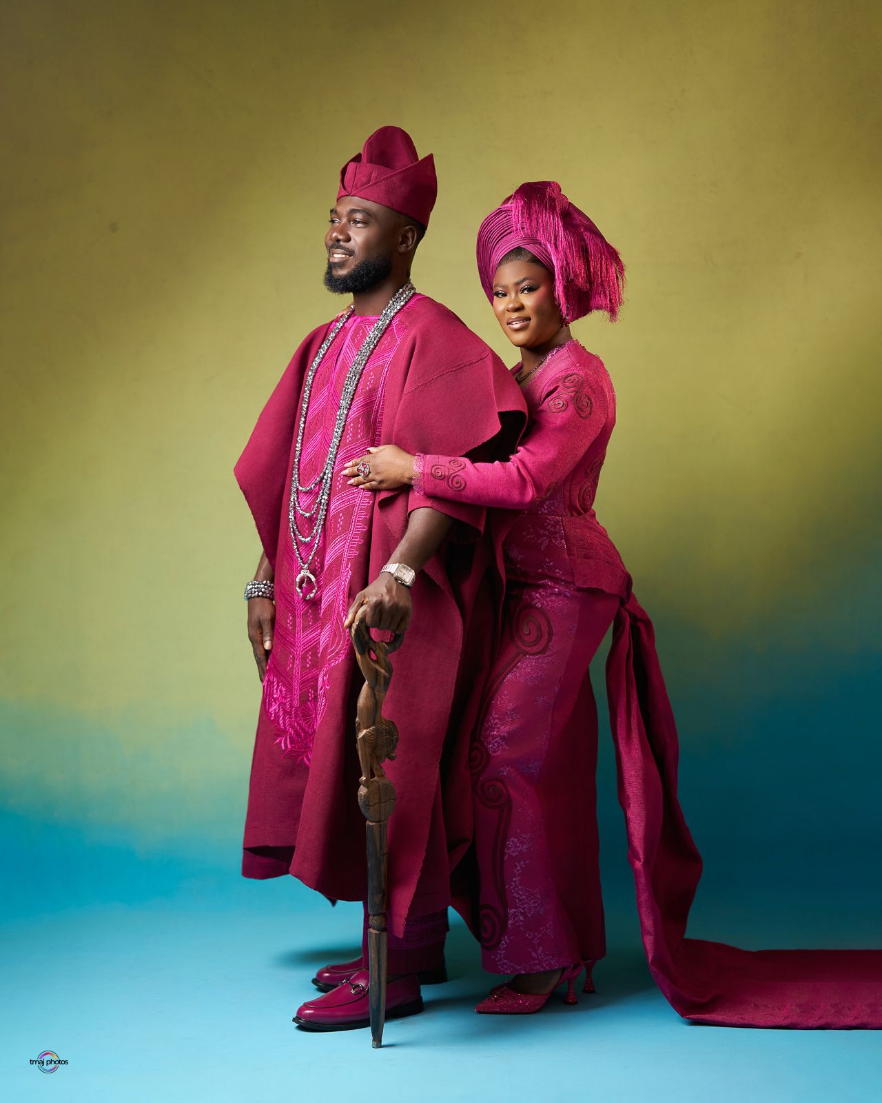 Couple in matching magenta Nigerian traditional attire with gele headwear posing elegantly for a pre-wedding photo shoot.