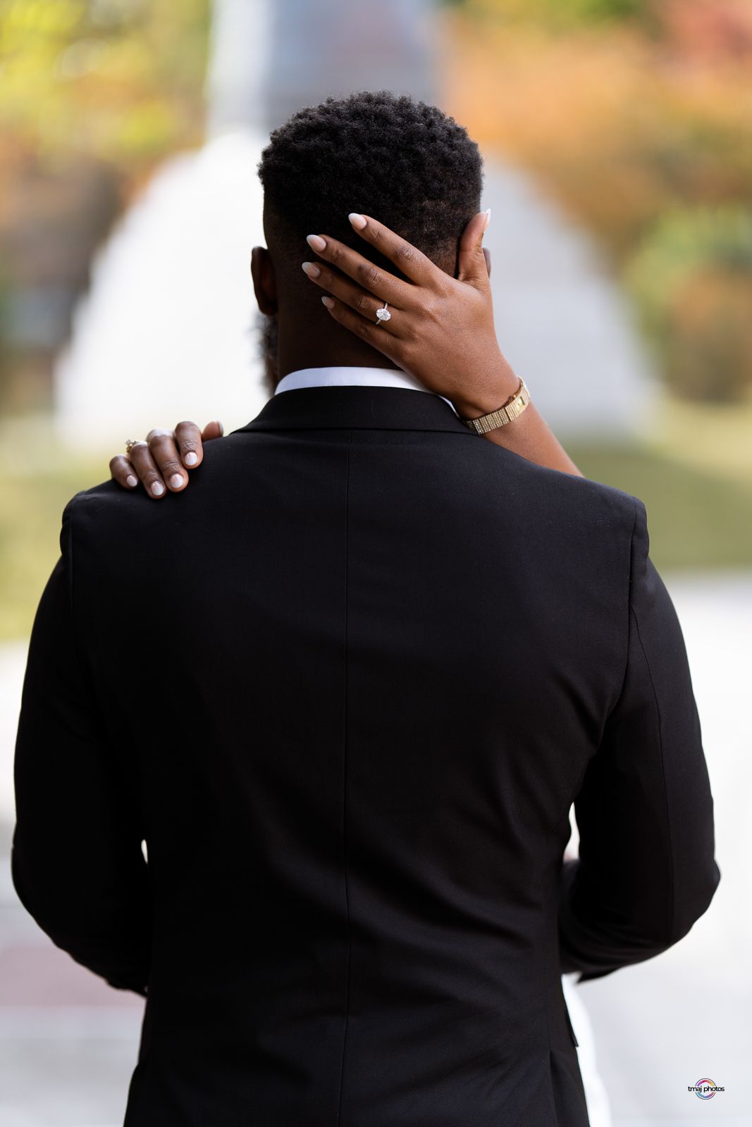 Woman placing hand on mans neck from behind in black suit.