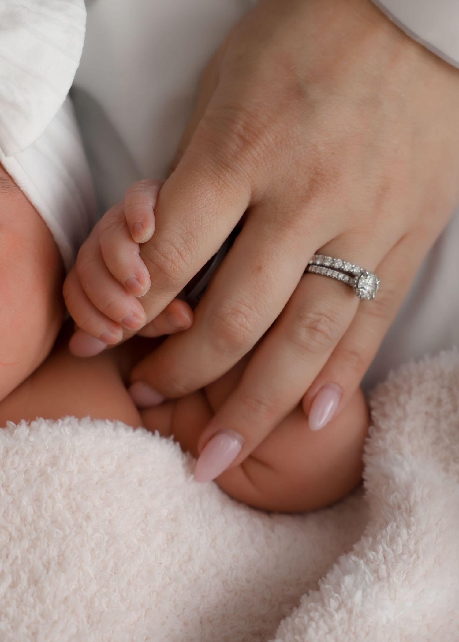 Mother's hand with diamond wedding ring gently held by newborn baby's tiny fingers.
by Andrew Fein Photography - Family and Newborn Photo