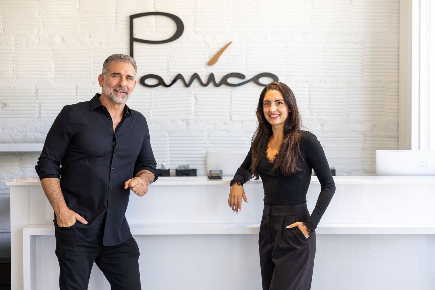 Man and woman in black outfits smiling together in front of a modern restaurant reception desk.
by Andrew Fein Photography - Family and Newb