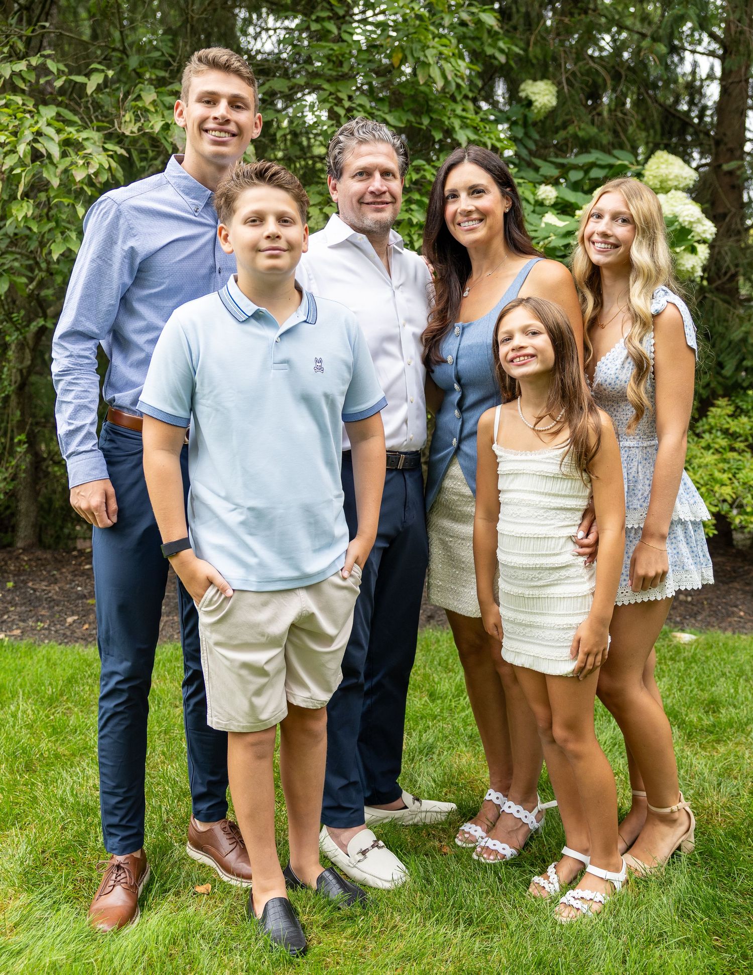 Happy family of six poses together outdoors in a lush green garden during a summer gathering.
by Andrew Fein Photography - Family and Newbor