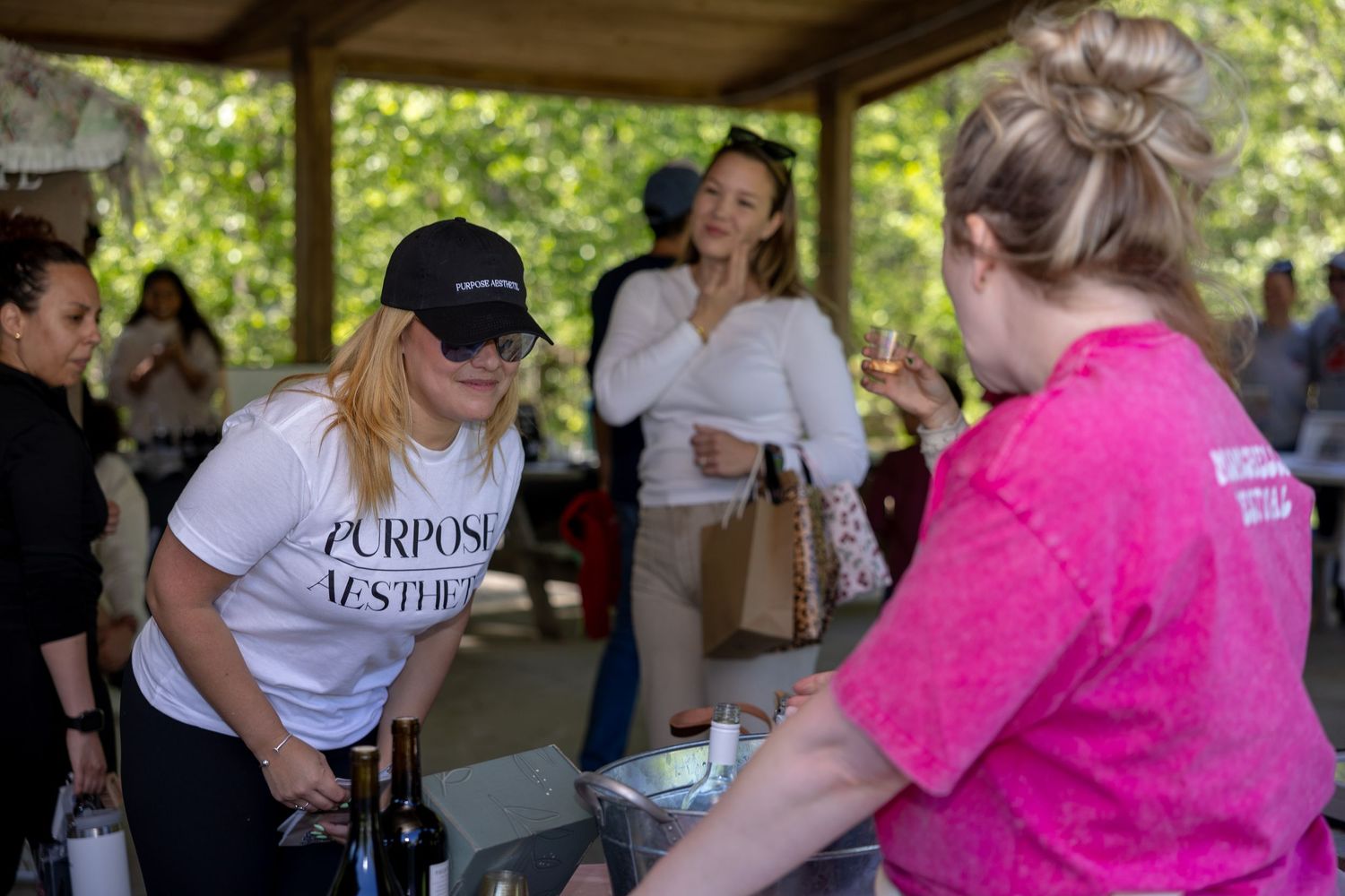 Woman in white Purpose Aesthetics shirt pouring wine at an outdoor tasting event.
by Andrew Fein Photography - Family and Newborn Photo