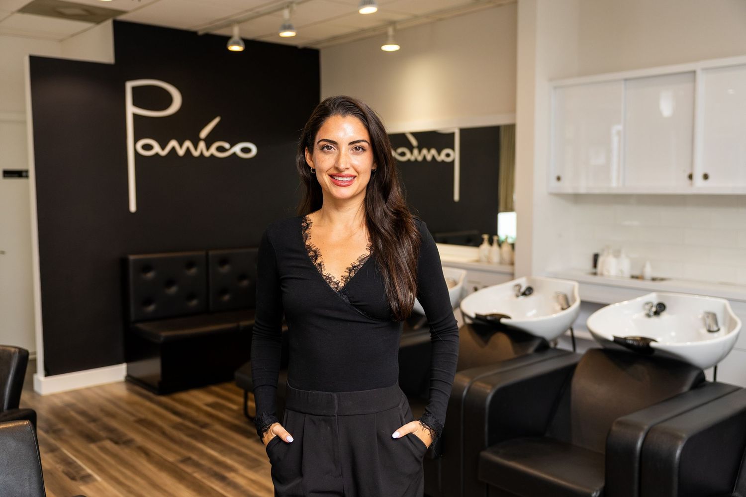 Smiling woman in black top poses inside Panico hair salon with wash basins in background.
by Andrew Fein Photography - Family and Newborn