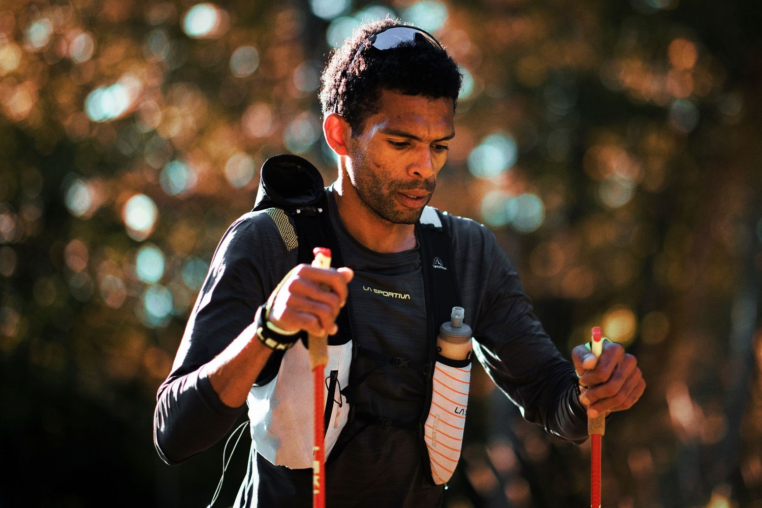 Trail runner with trekking poles and hydration vest preparing during an outdoor ultramarathon race.