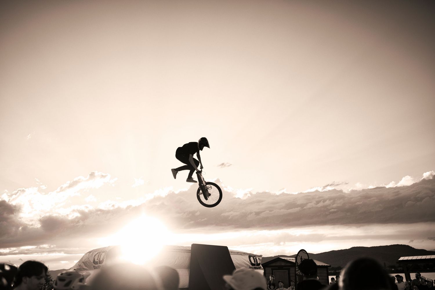 Silhouette of a BMX rider performing a trick high in the air against a dramatic sunset sky.