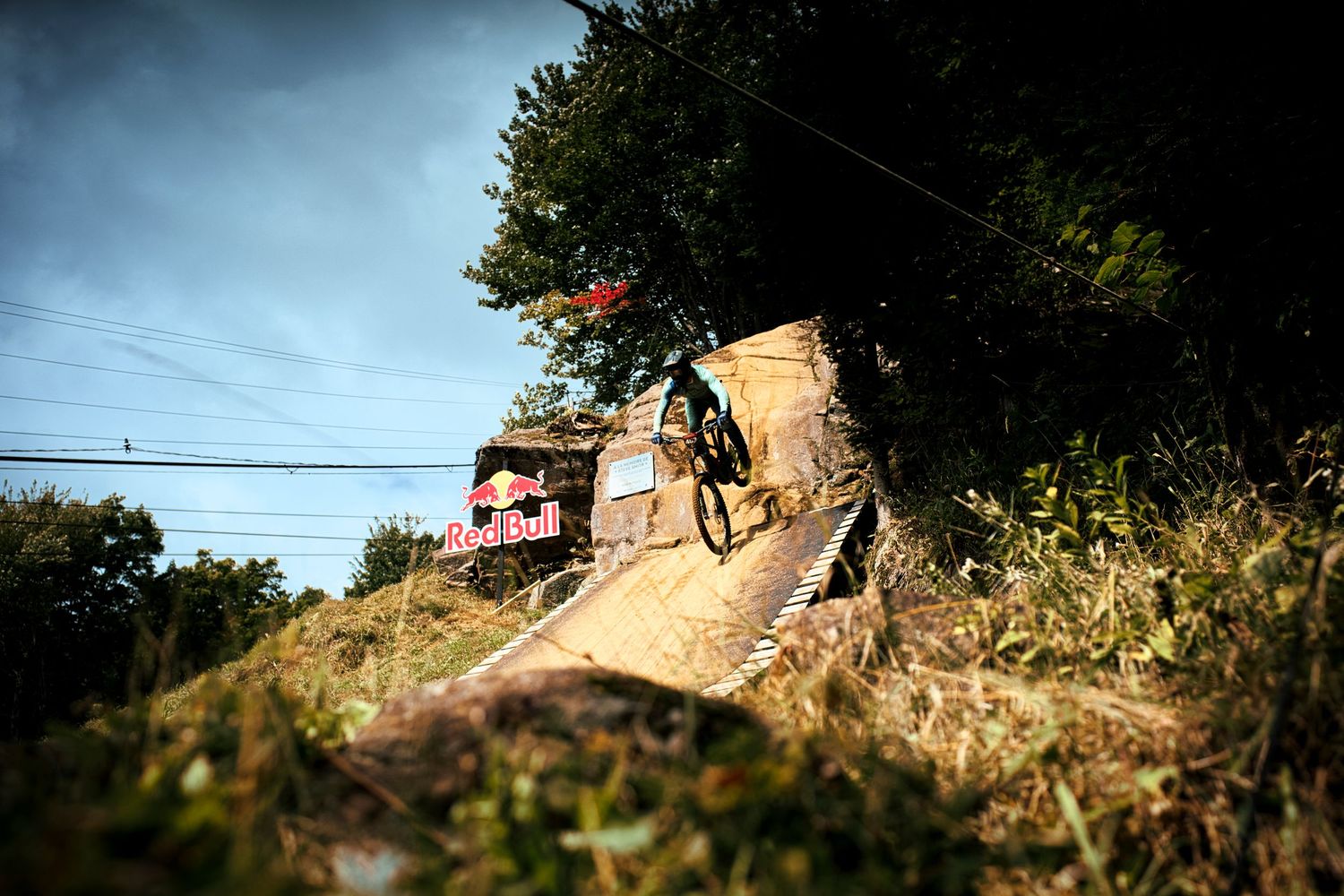 Mountain biker launching off Steve Smith drop near Red Bull banner during downhill event by Dave Clément, Québec.