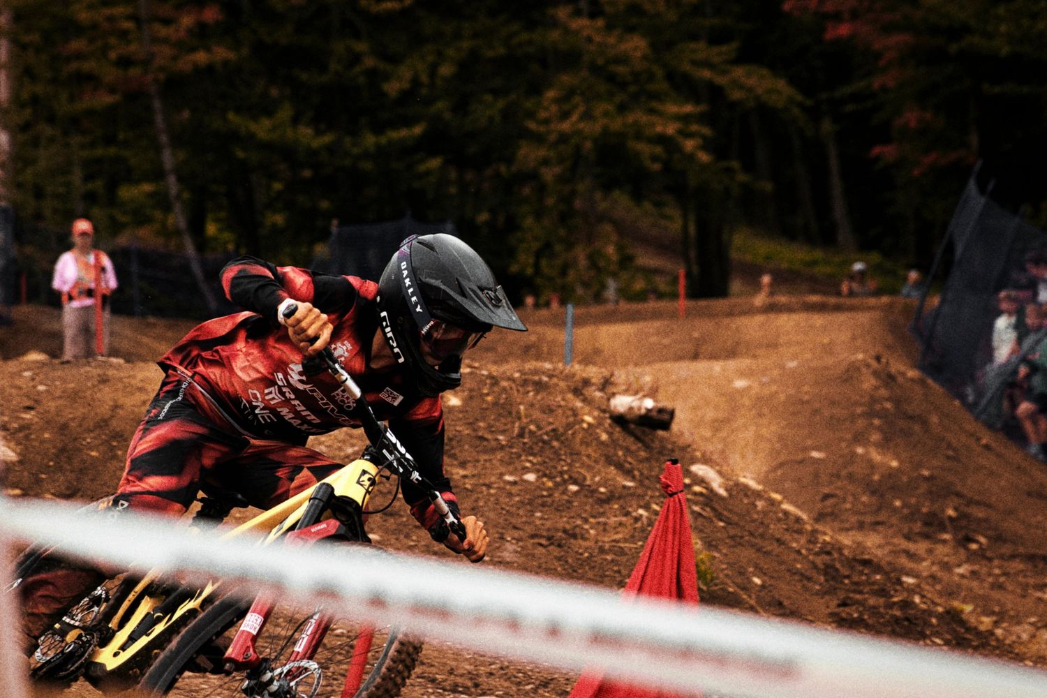 Mountain biker in red and black gear racing a dual slalom race at Mont-Sainte-Anne by Dave Clément.