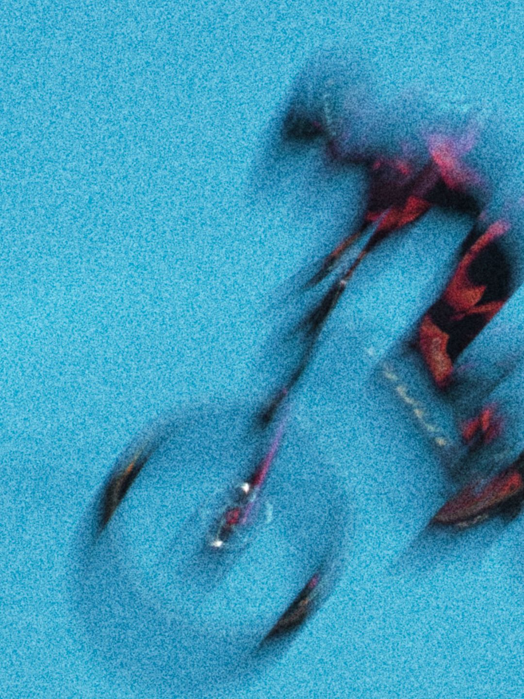 Abstract motion blur photograph of a mountain biker in red gear against a vivid teal background by Dave Clément, Québec.