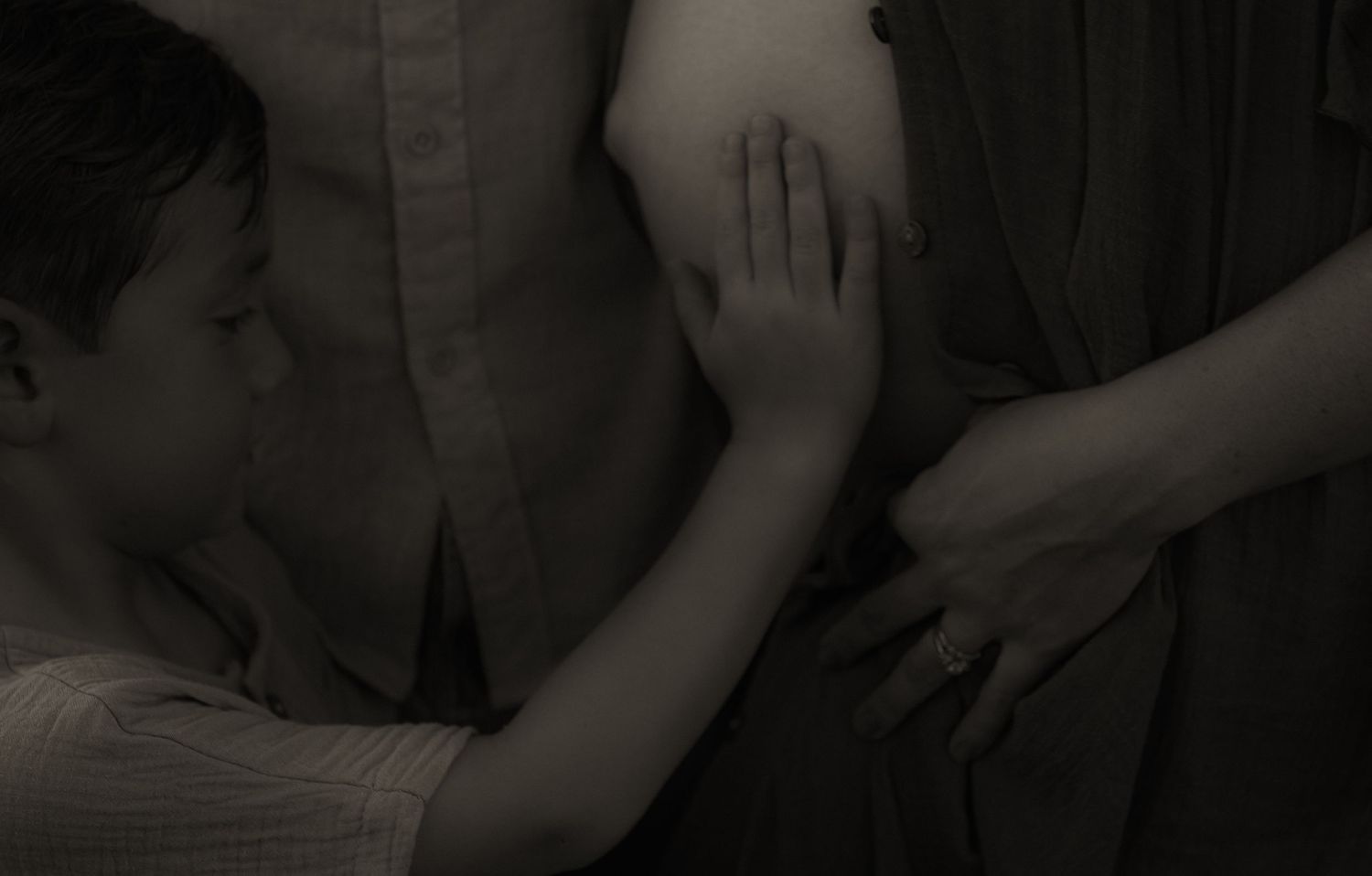 Black and white photo of people standing close together, hands gently touching in an intimate moment.