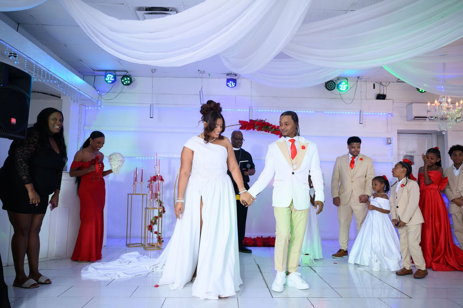 Bride and groom share first dance at elegant wedding reception with guests in red and white attire.