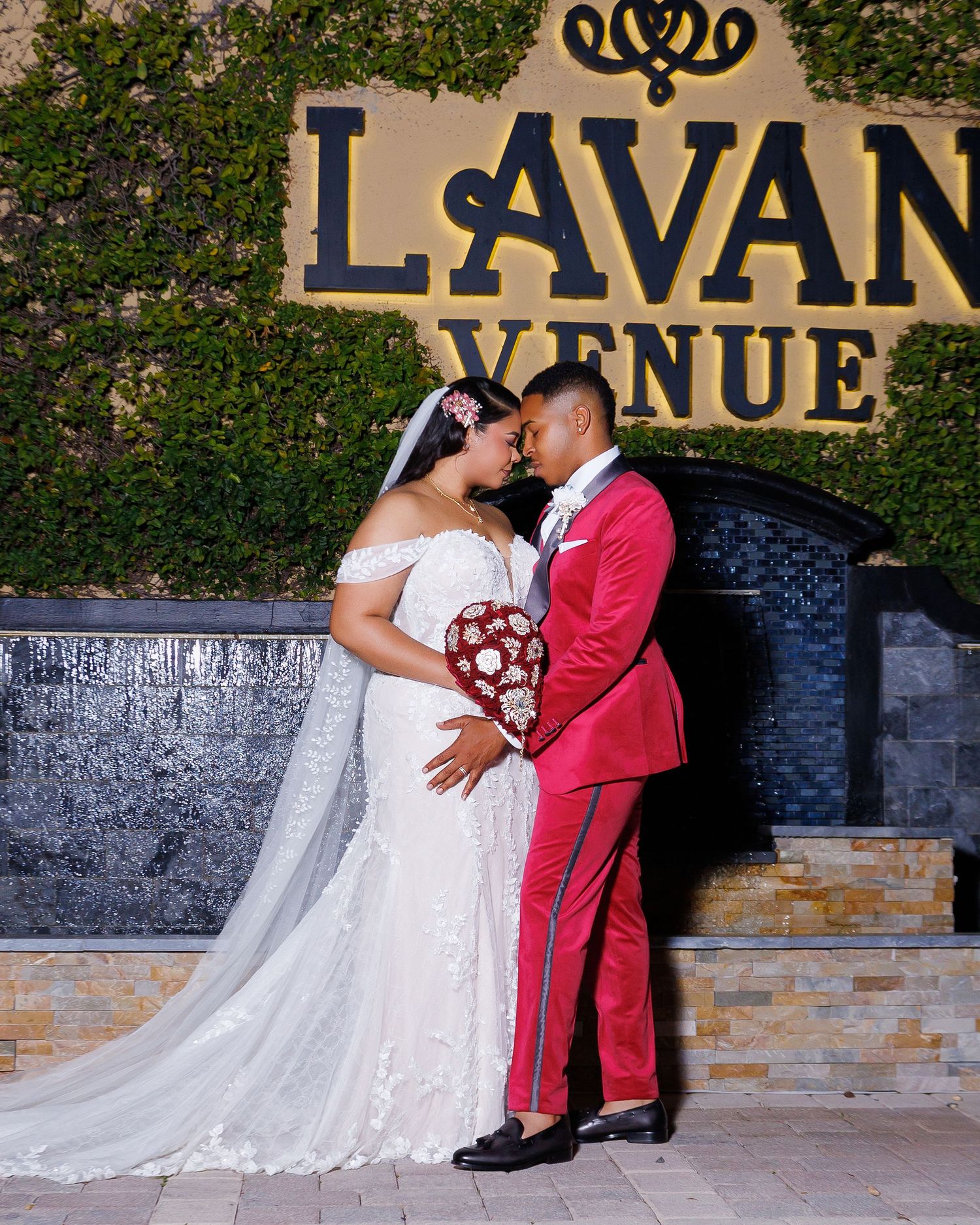 Bride and groom share a romantic moment at LaVan Avenue Venue, she in white lace gown, he in pink tuxedo.