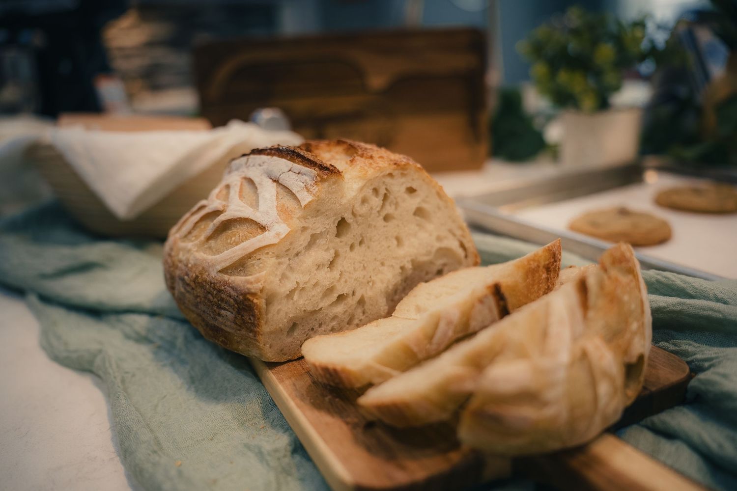 Freshly sliced sourdough bread loaf on a wooden cutting board with a rustic kitchen background.