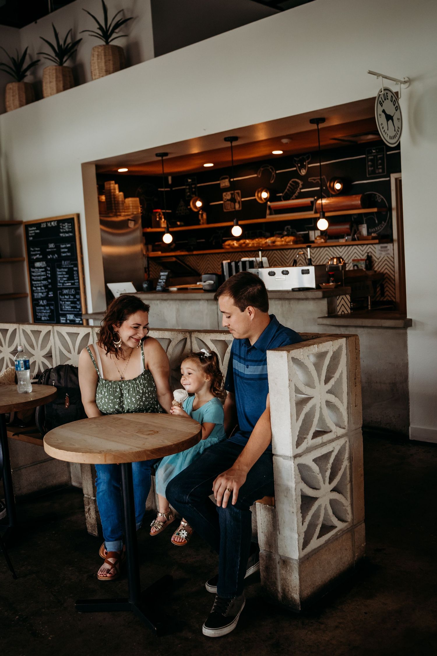 Family of three enjoying time together at a cozy cafe with rustic decor.