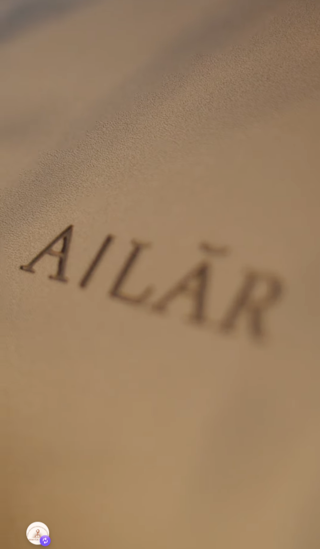 Close-up of embossed AILAR text on beige textured surface.
