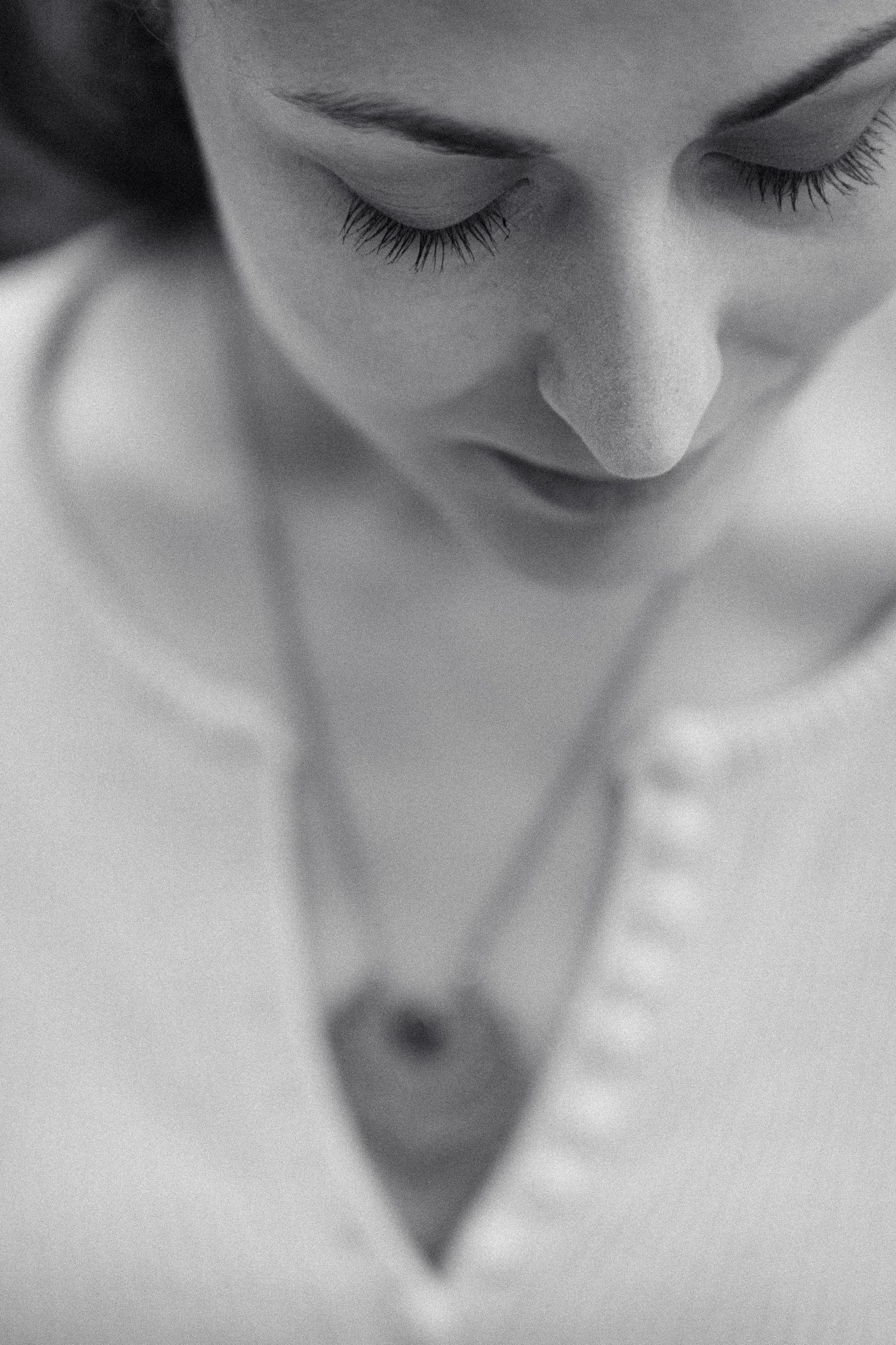 Black and white close-up portrait of a woman with closed eyes wearing a heart pendant necklace.