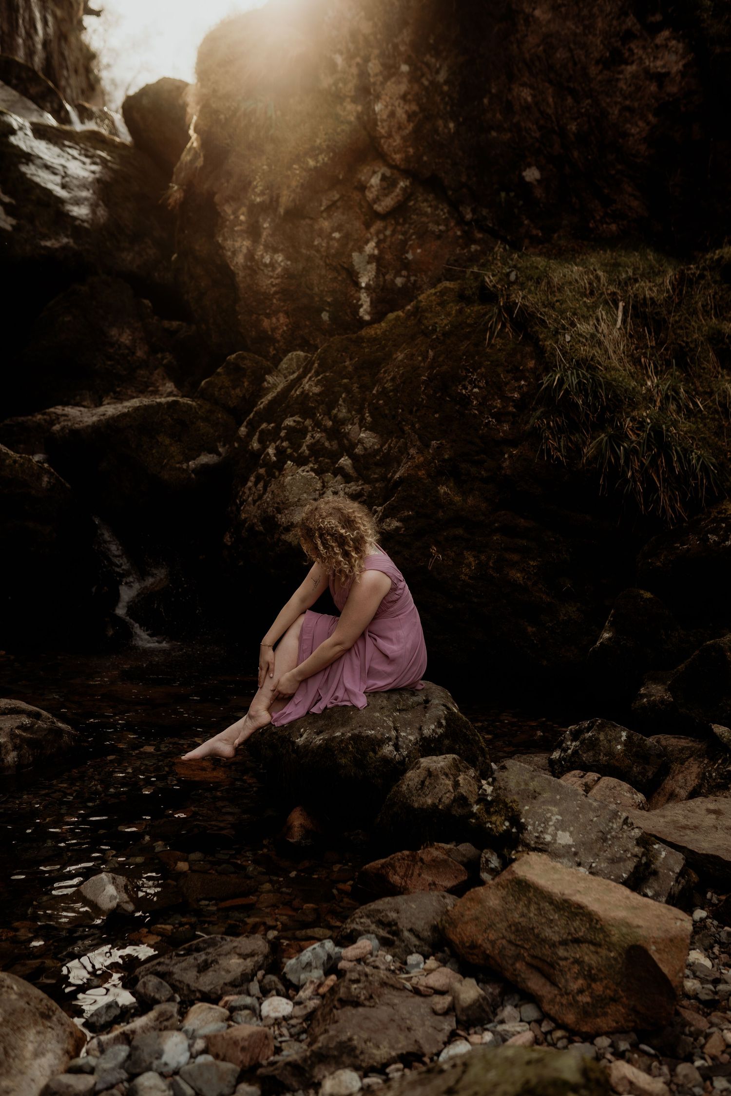 Desirée in een roze jurk bij een waterval in Glencoe bij de Three Sisters, Schotland