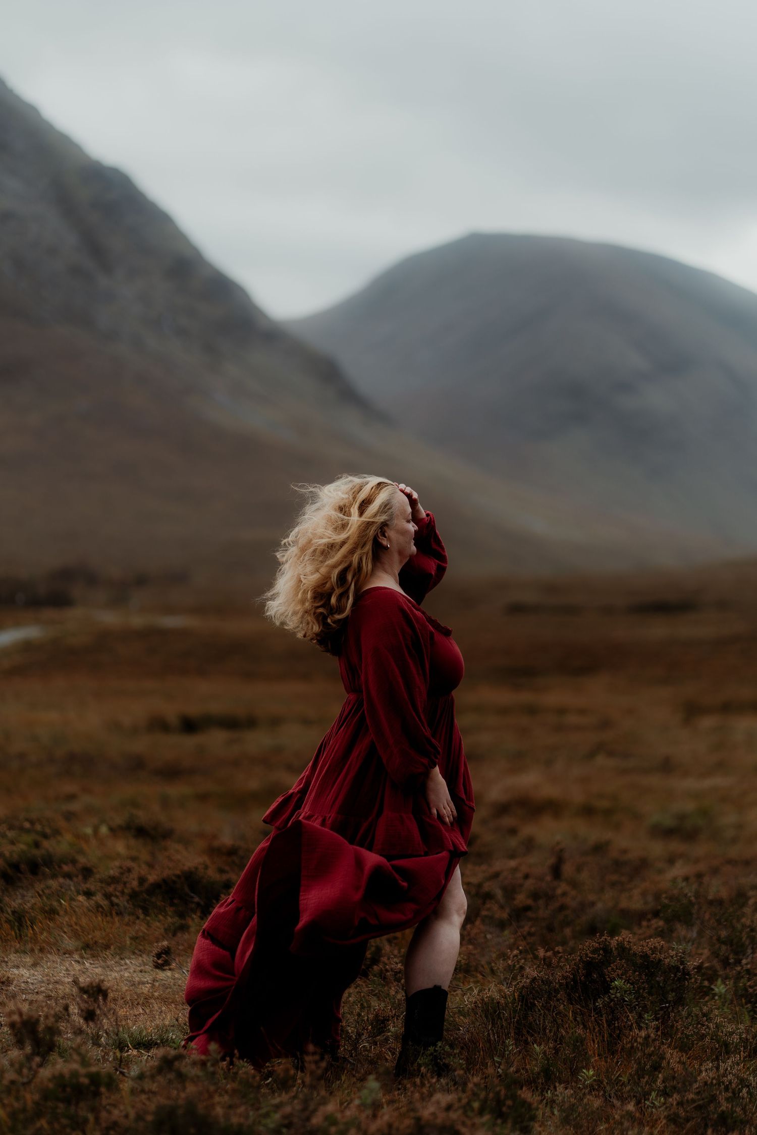 Dramatic sequence of a person in a flowing red dress walking across a misty Scottish Highland landscape with mountains.
