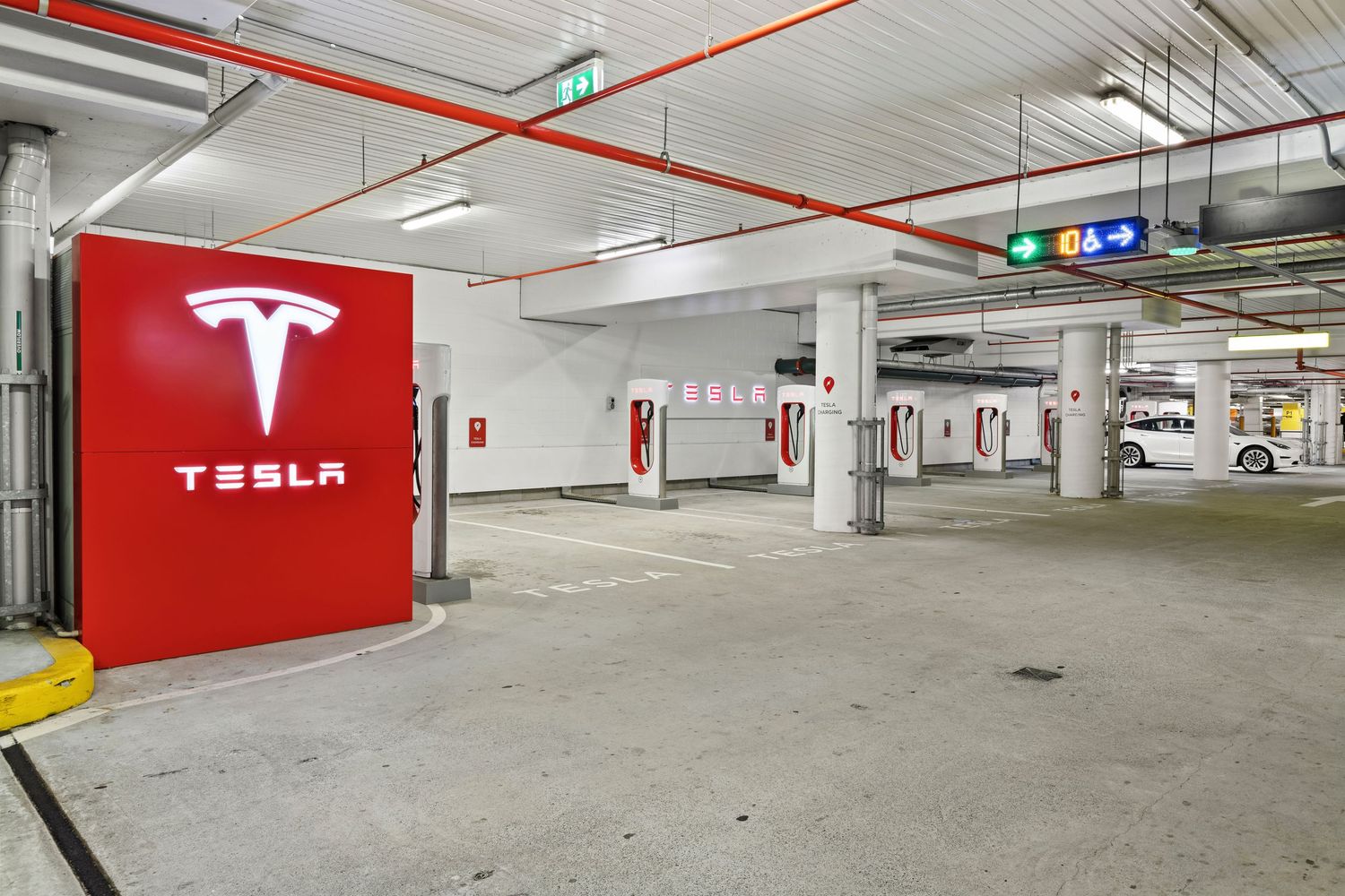 Photograph of a Tesla electric vehicle charging area in a parking garage.