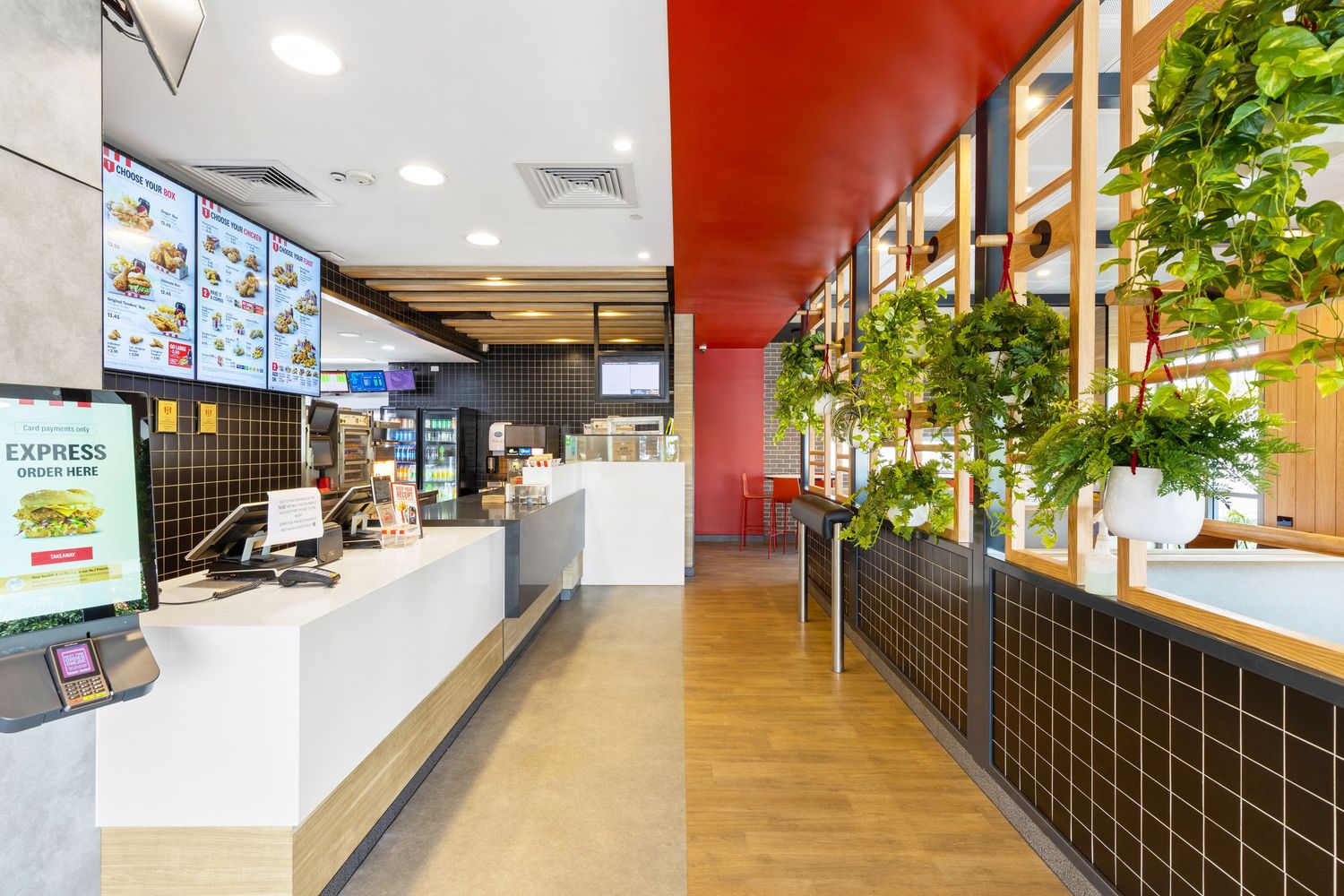 Interior photograph of a fast food or cafe service counter with red feature wall.