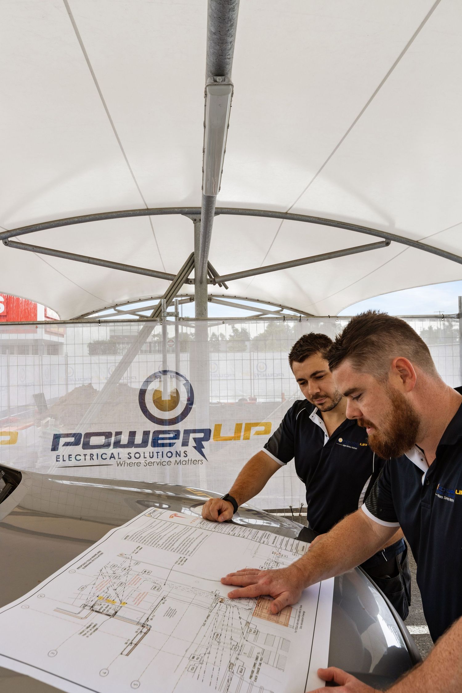 Construction photograph of a worker reviewing building plans on site.