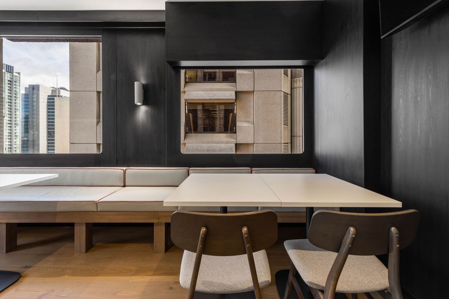 Interior photograph of a dark-toned meeting or dining space with city views.
