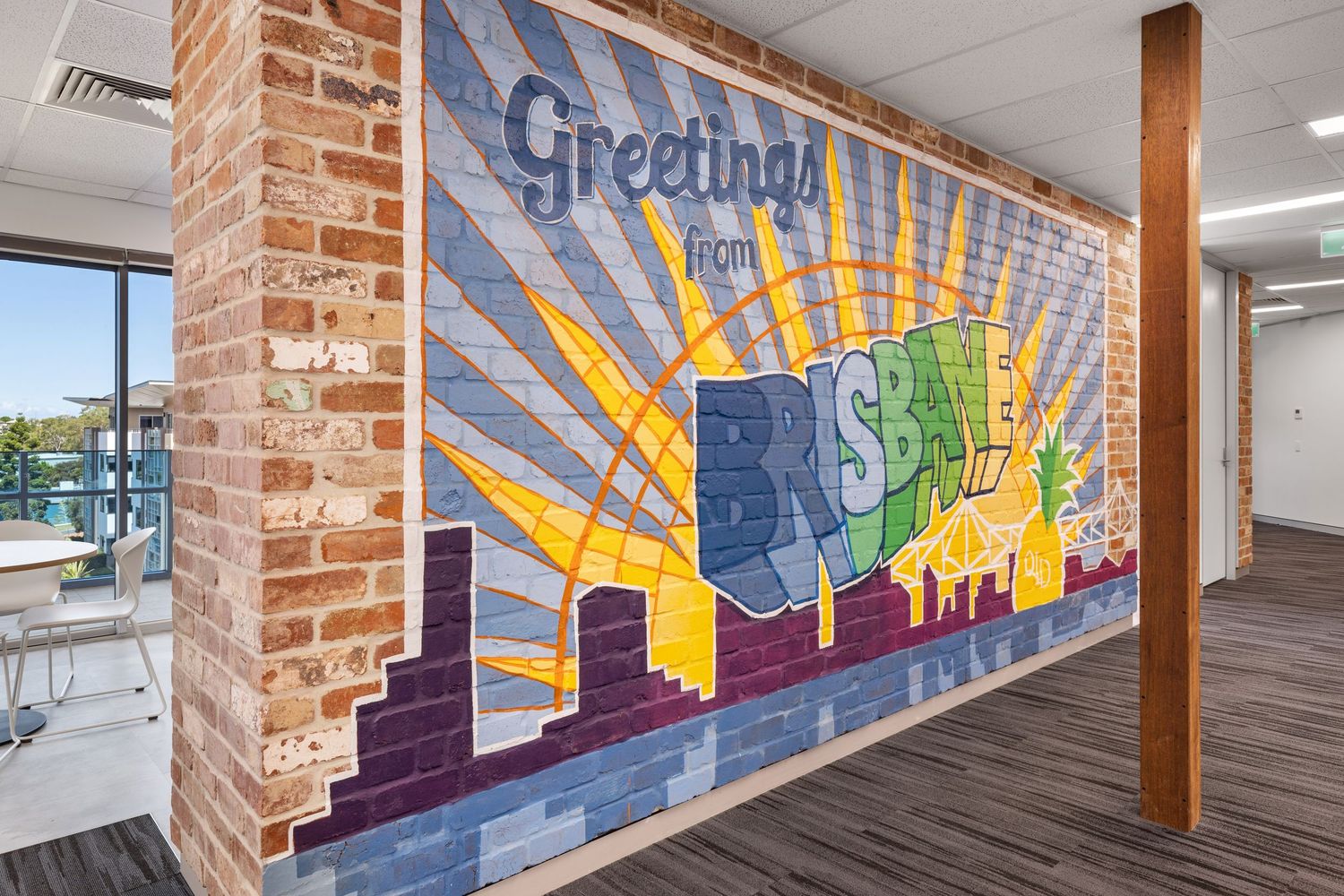 Interior photograph of a mural wall reading 'Greetings' with brick surrounds.