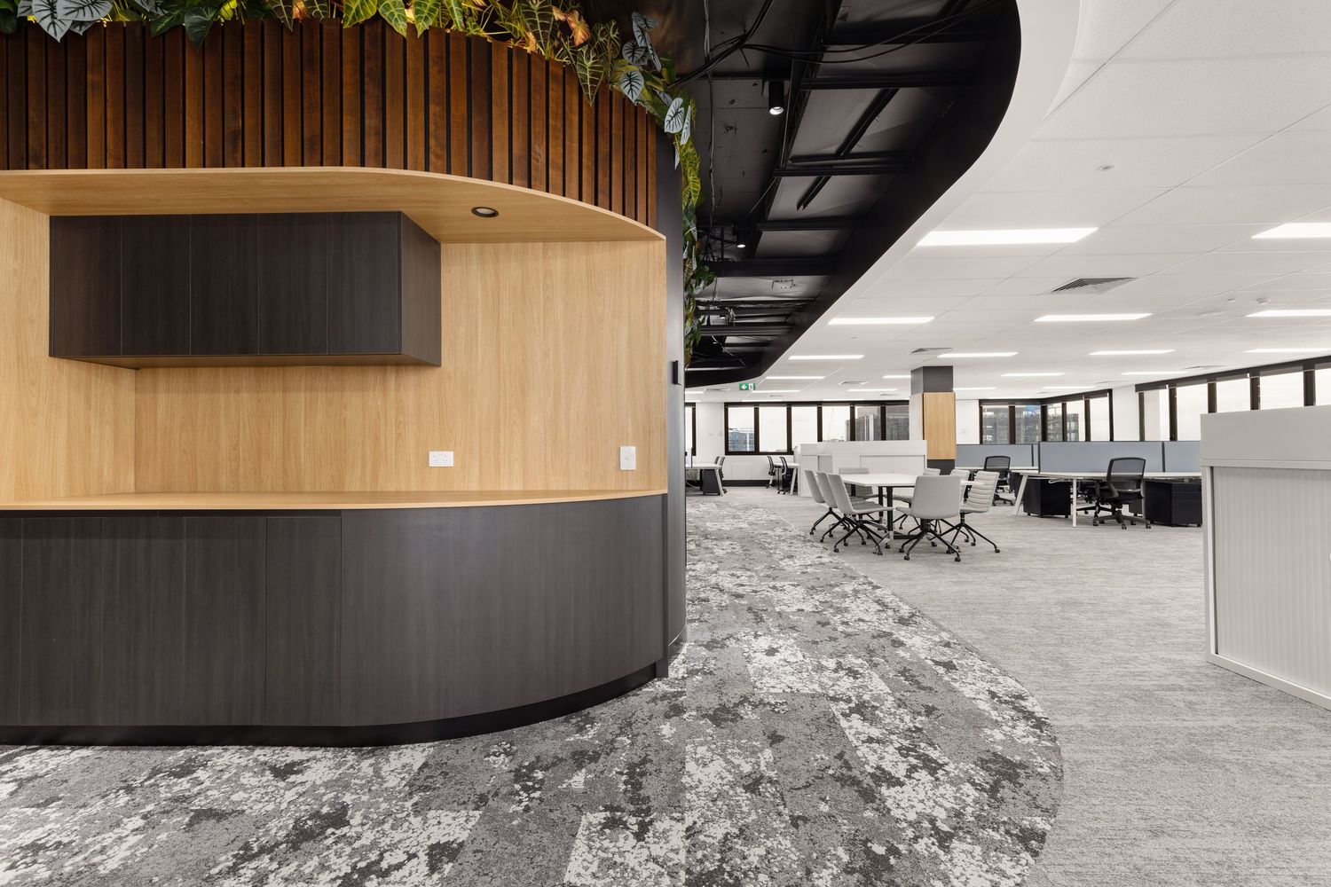 Interior photograph of a modern reception desk area with open-plan office beyond.